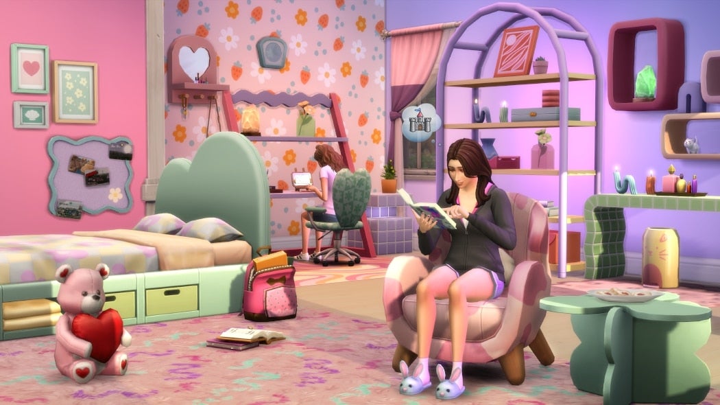 A woman sits on a heart-covered chair in a purple and pink room with lots of pastel, patterned textures.