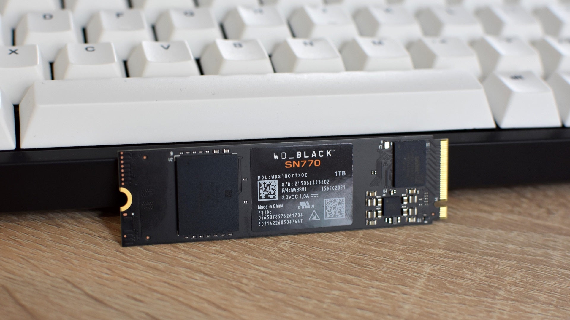 The WD Black SN770 SSD propped up against a gaming keyboard.