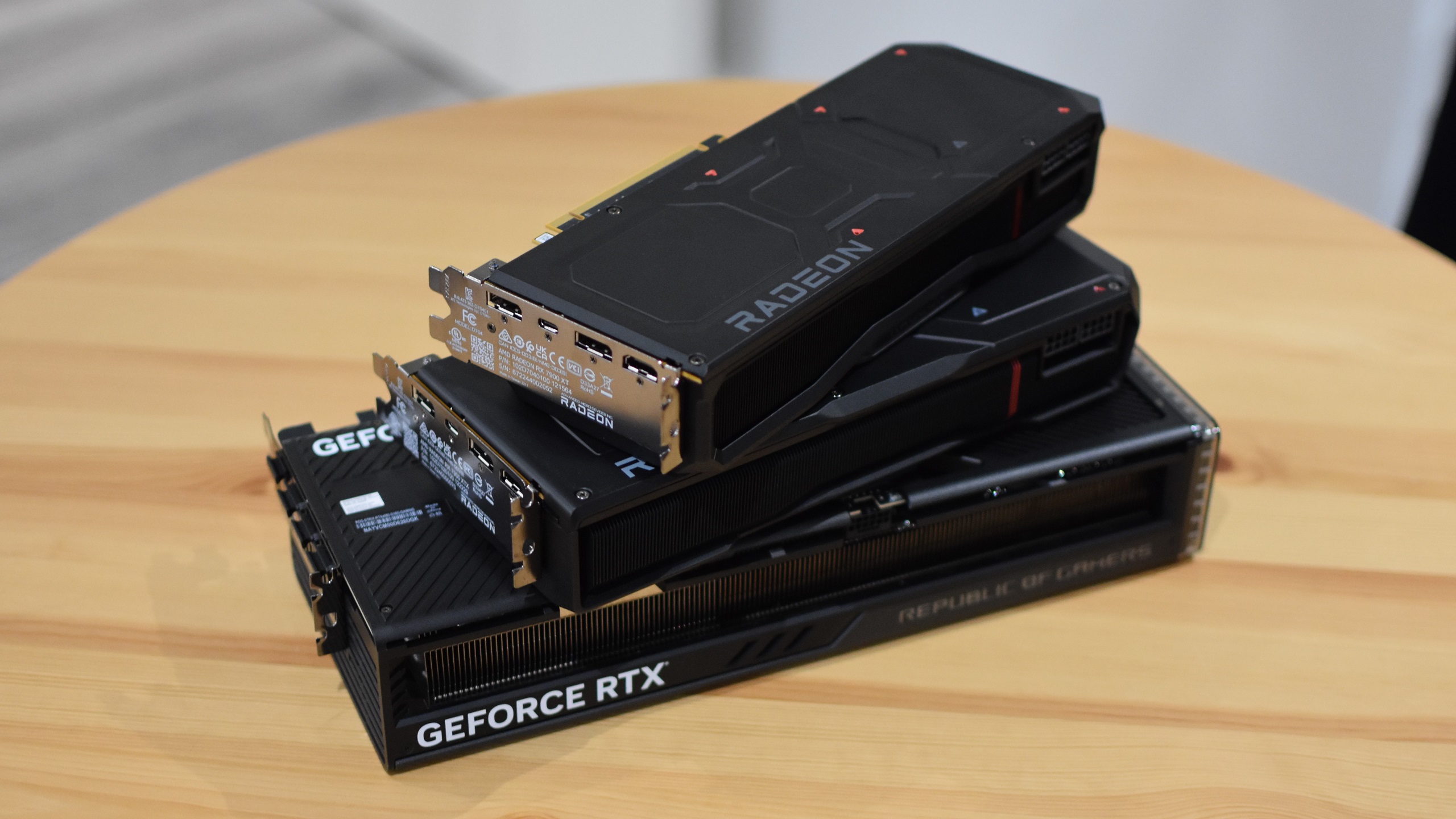The AMD Radeon RX 7900 XT and Radeon RX 7900 XTX graphics cards stacked on top of an RTX 4080.
