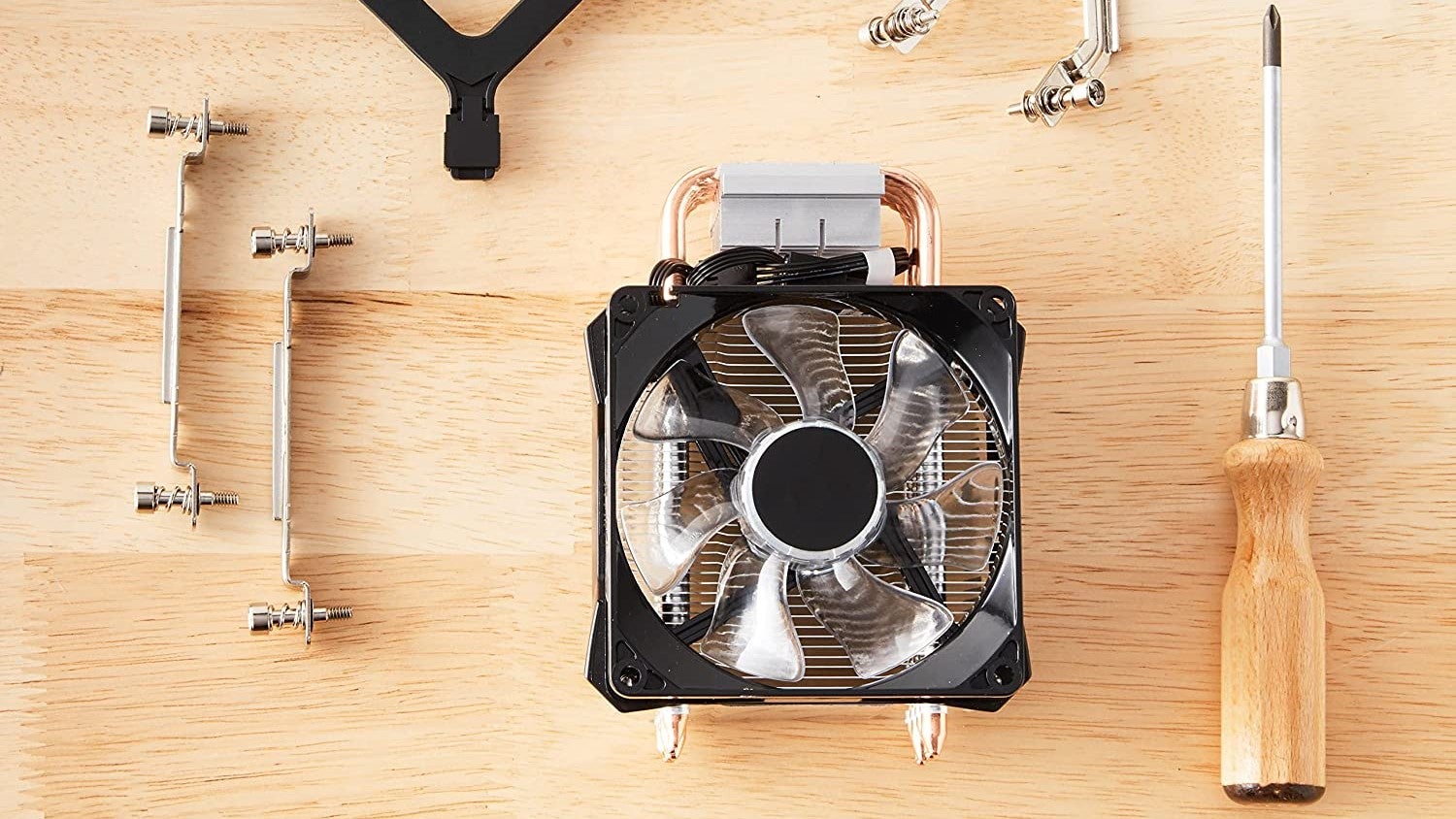 The Amazon Basics Computer Cooling Fan on a table, next to some of its mounting hardware and a screwdriver.