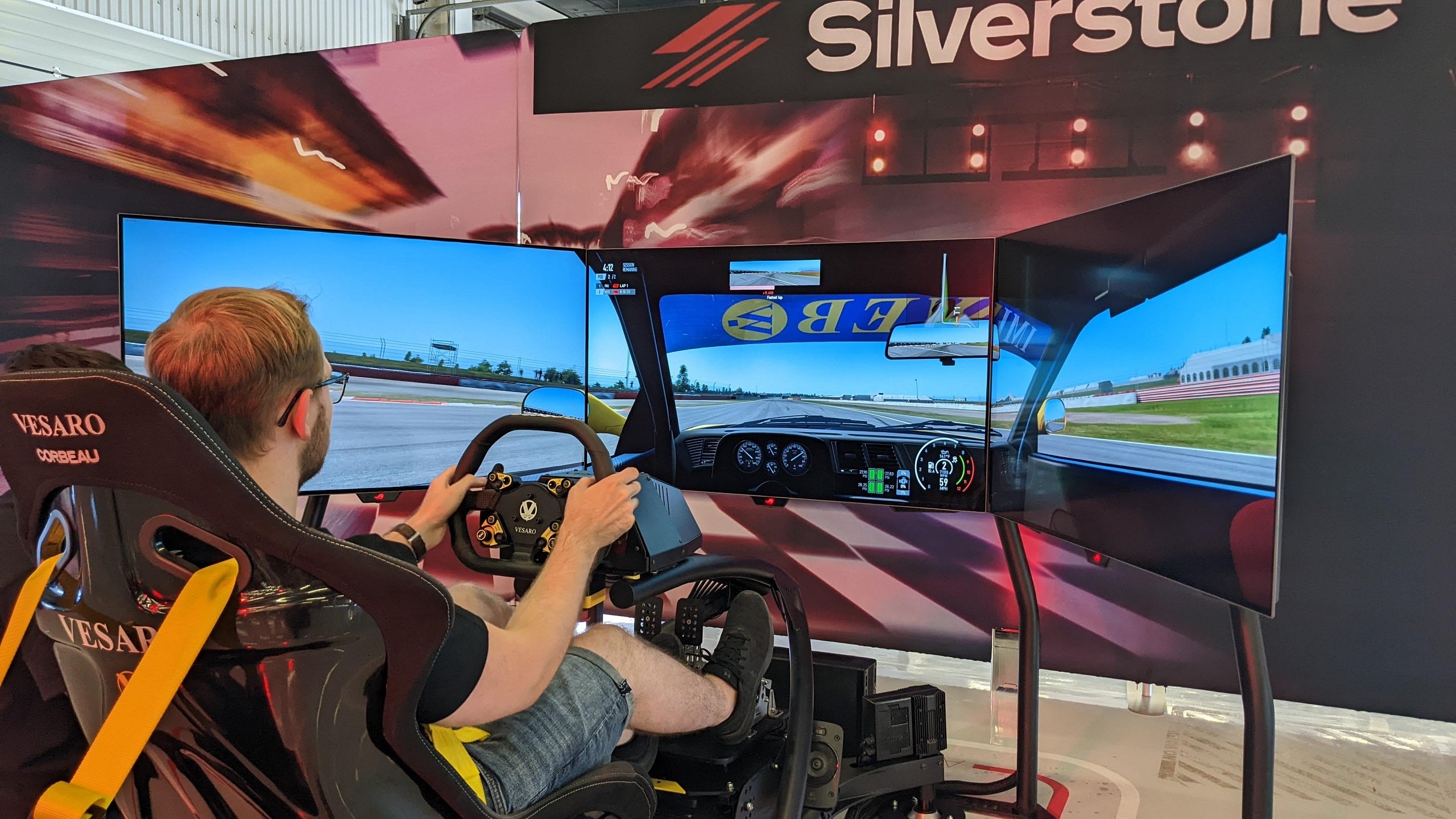 Three Asus ROG Swift PG48UQ gaming monitors arranged in front of a racing sim rig.