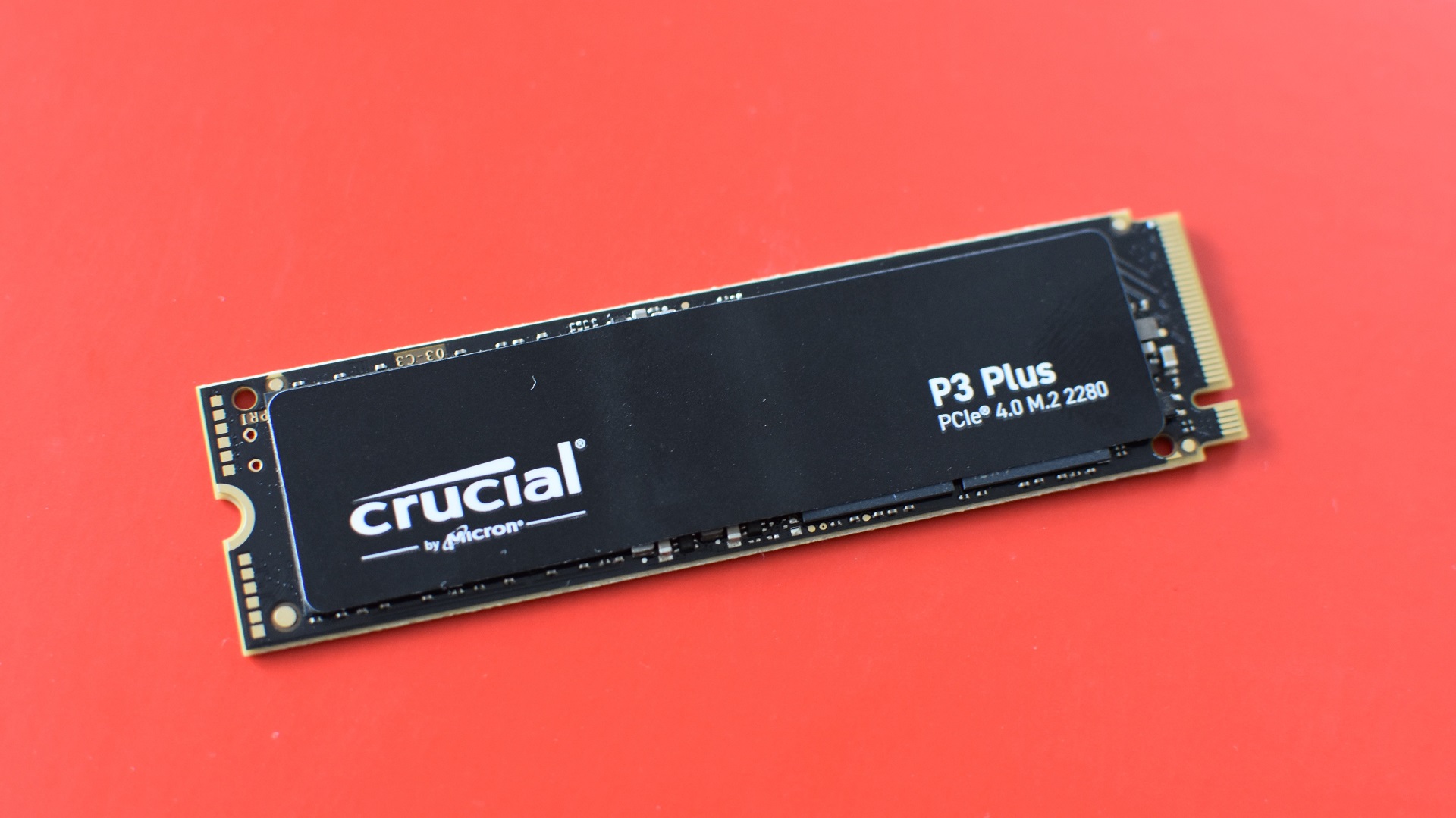 The Crucial P3 Plus SSD against a red background.