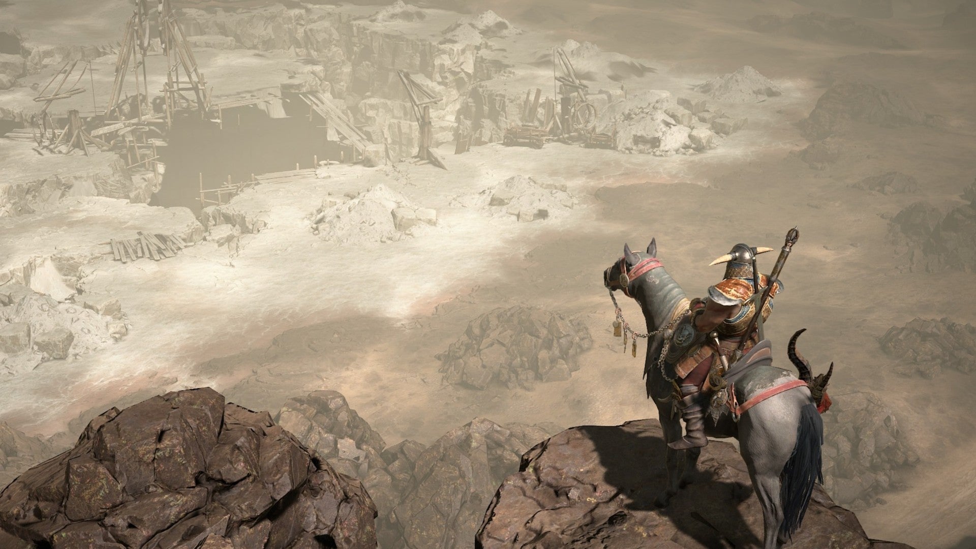 Un bárbaro mira por encima del borde de un acantilado hacia una ciudad en Diablo 4.