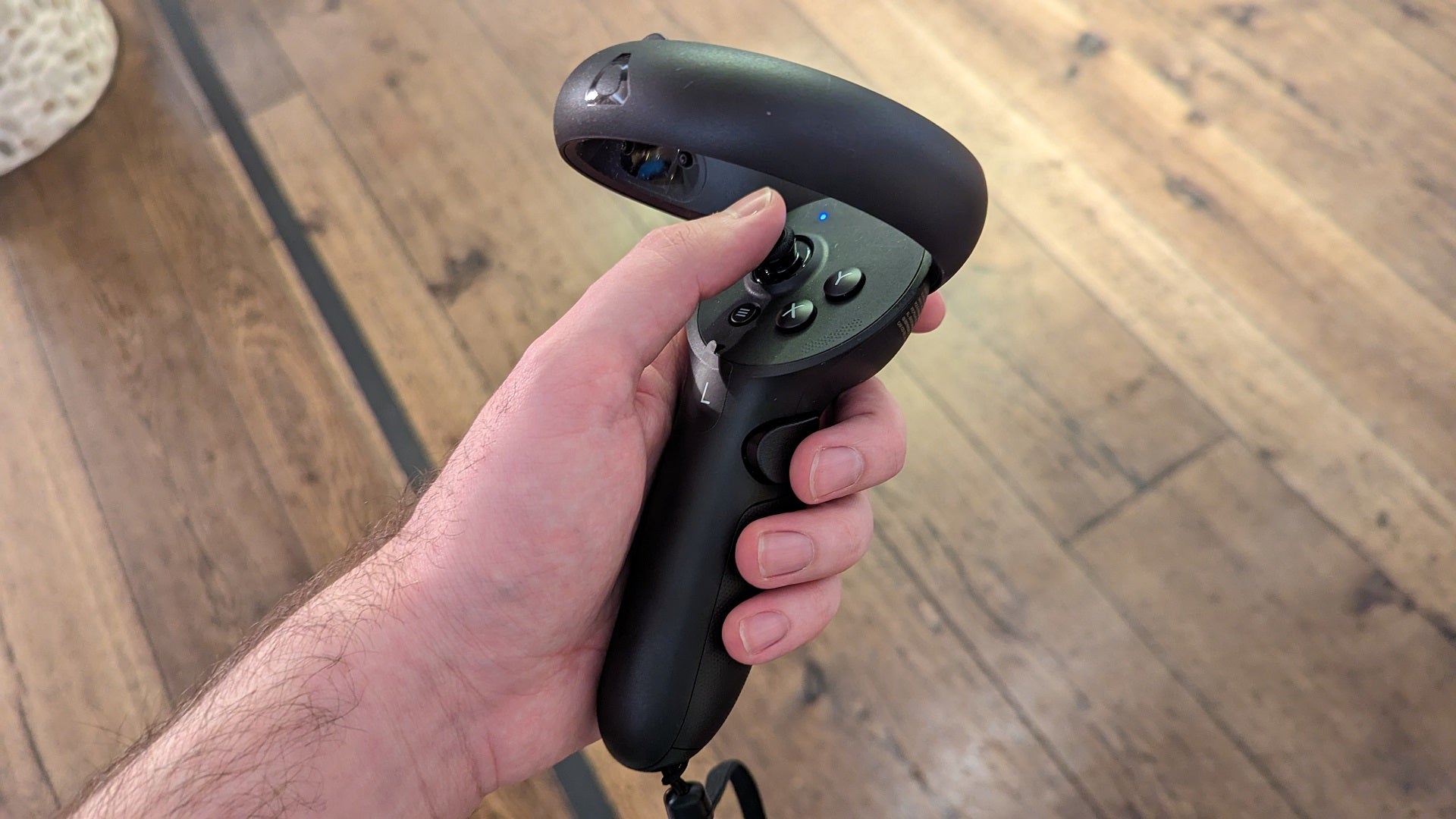 A Vive XR Elite controller being held in a hand.