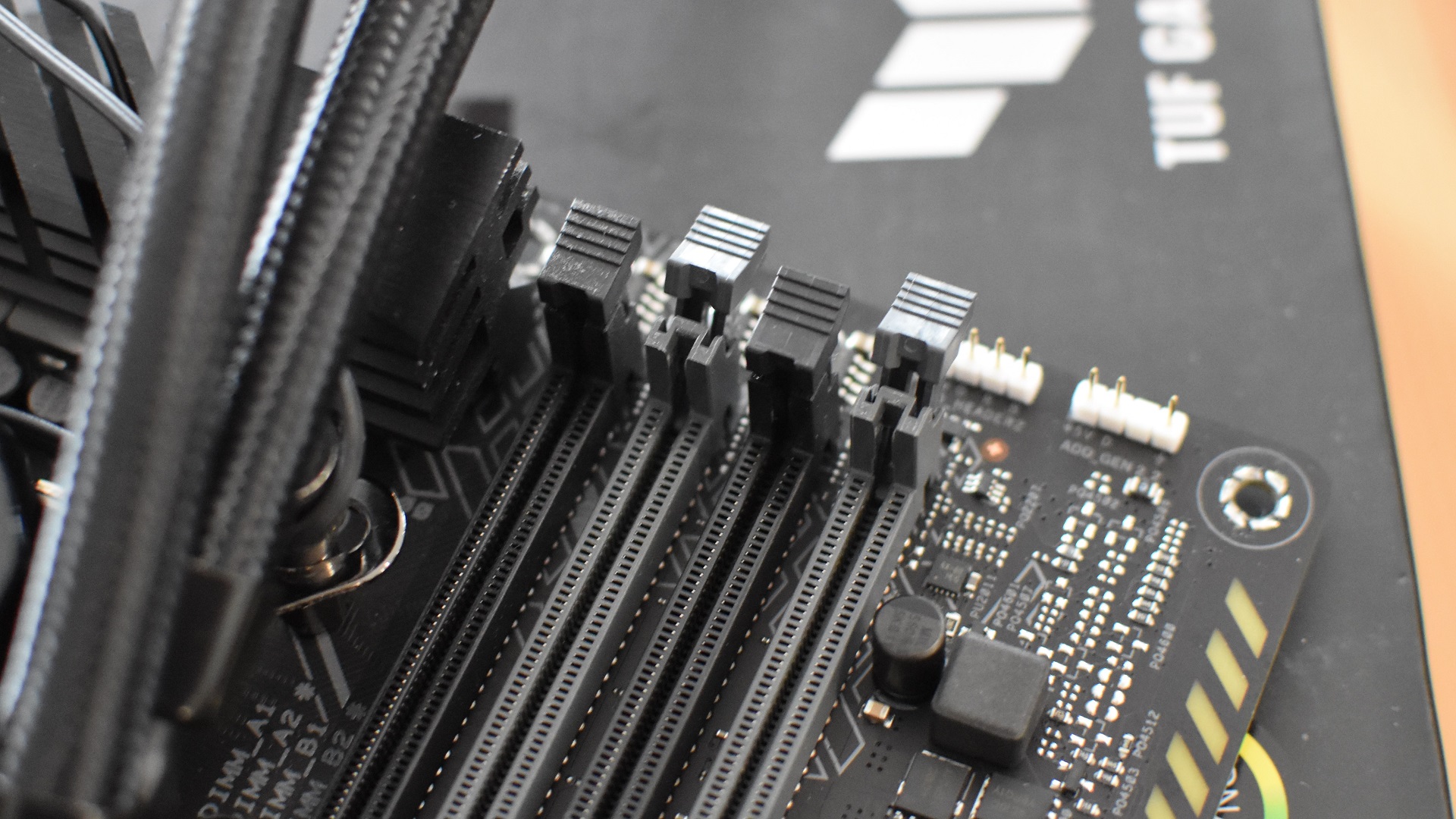 Paso 2 de cómo instalar RAM: identifique las ranuras de RAM correctas para usar, luego abra sus clips de retención de plástico.