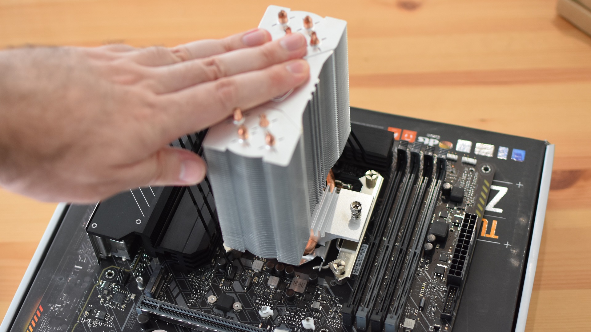 Step 4b of how to install a CPU air cooler: press the cooler down on the CPU and attach it securely to the mounting hardware.