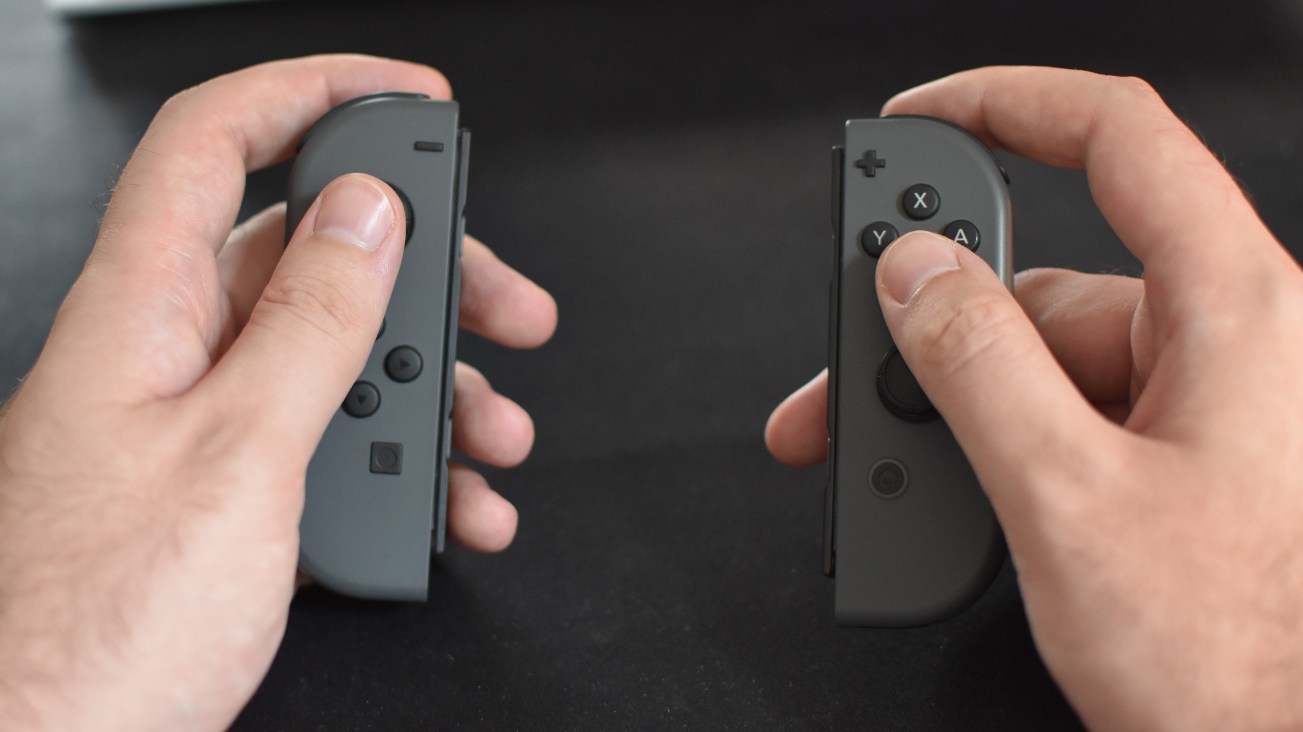 A pair of hands holding a set of Nintendo Joy-Cons.