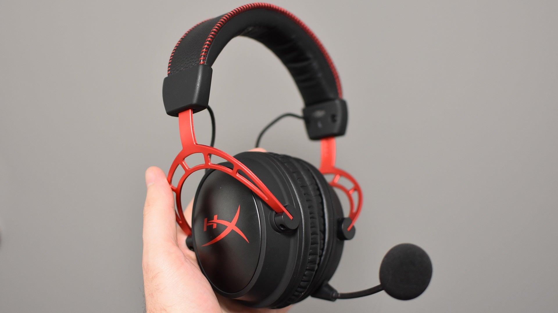 A hand holding up the HyperX Cloud Alpha Wireless gaming headset.