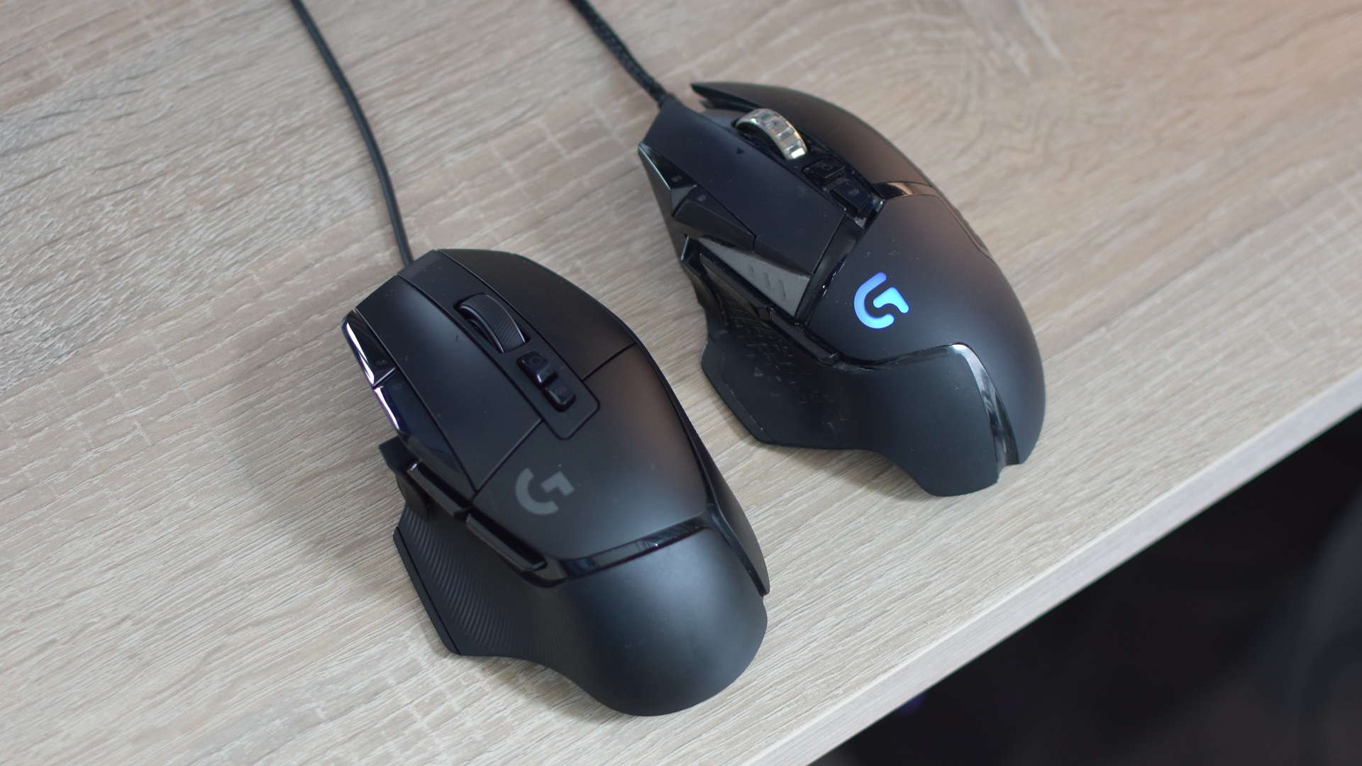 The Logitech G502 X gaming mouse next to a G502 Proteus Spectrum on a desk.