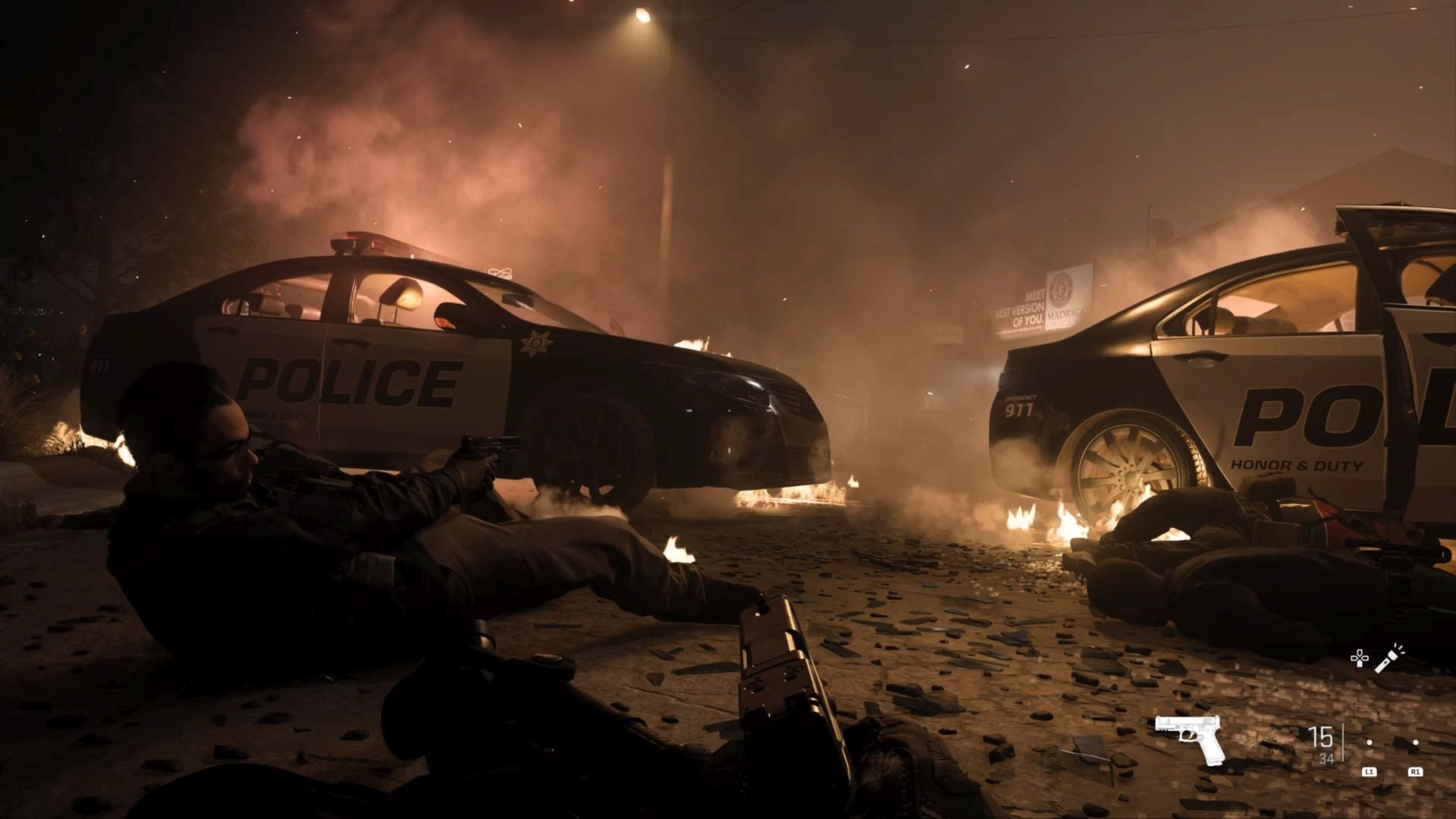 Two burning police cars crashed in a street at night, with the player character lying prone next to a police officer