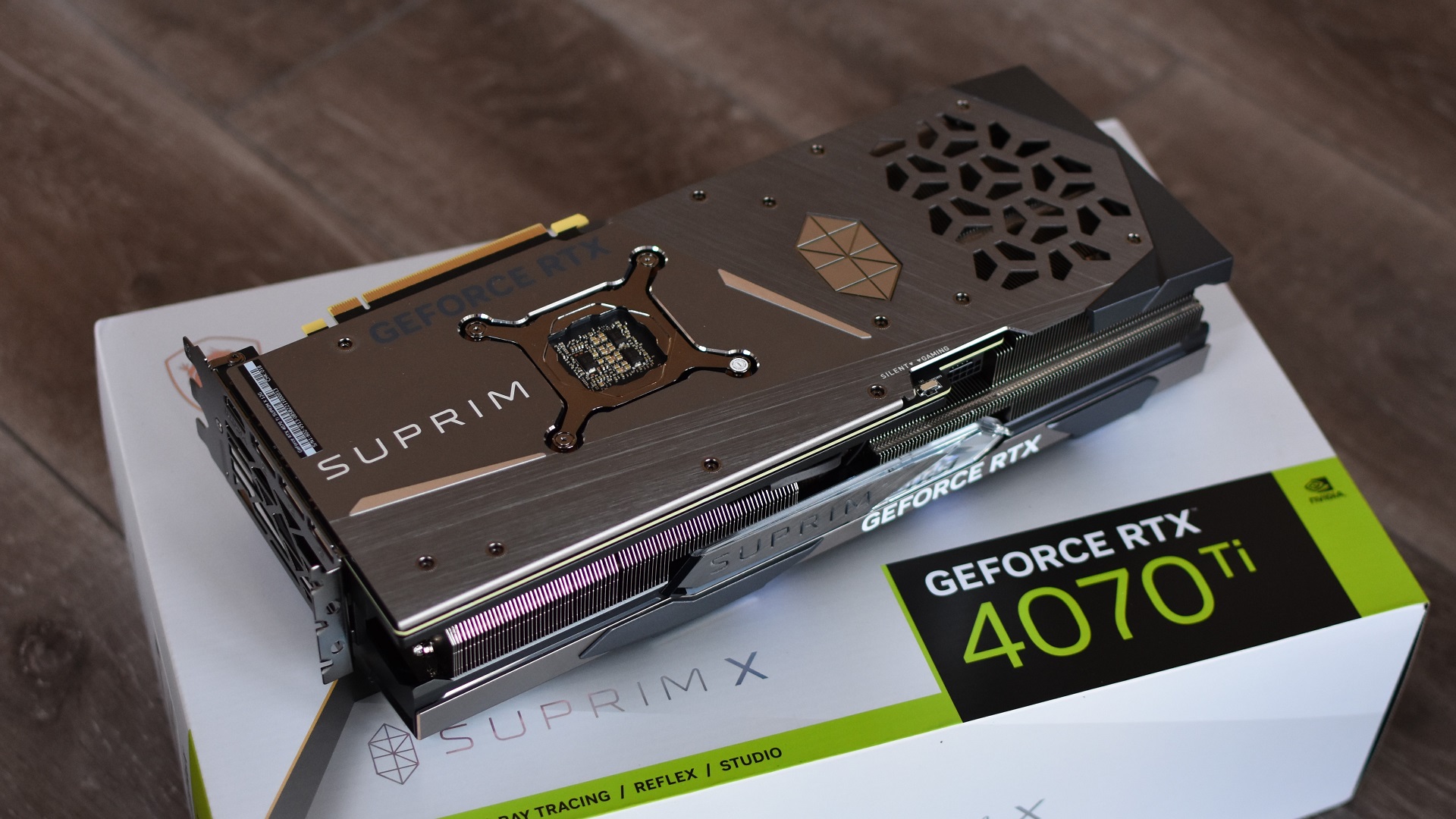 MSI GeForce RTX 4070 Ti Suprim X 12G grafikkort, satt med baksidan uppåt, ovanpå sin egen låda.