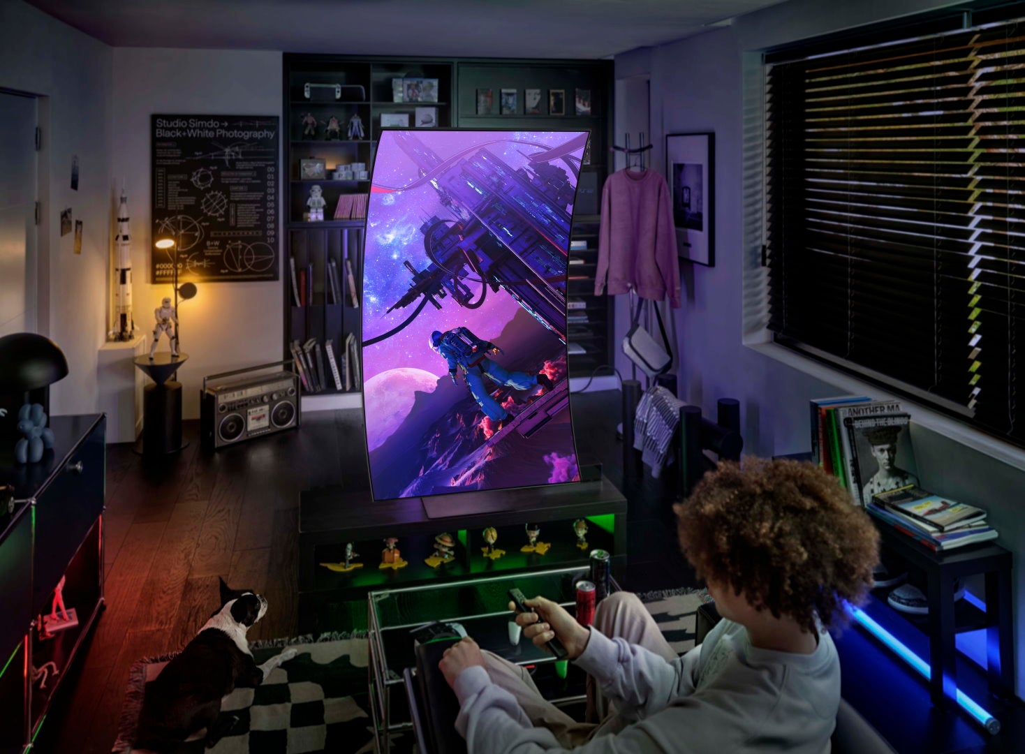 A young person pretends to play a game in portrait mode on the Samsung Odyssey Ark gaming monitor