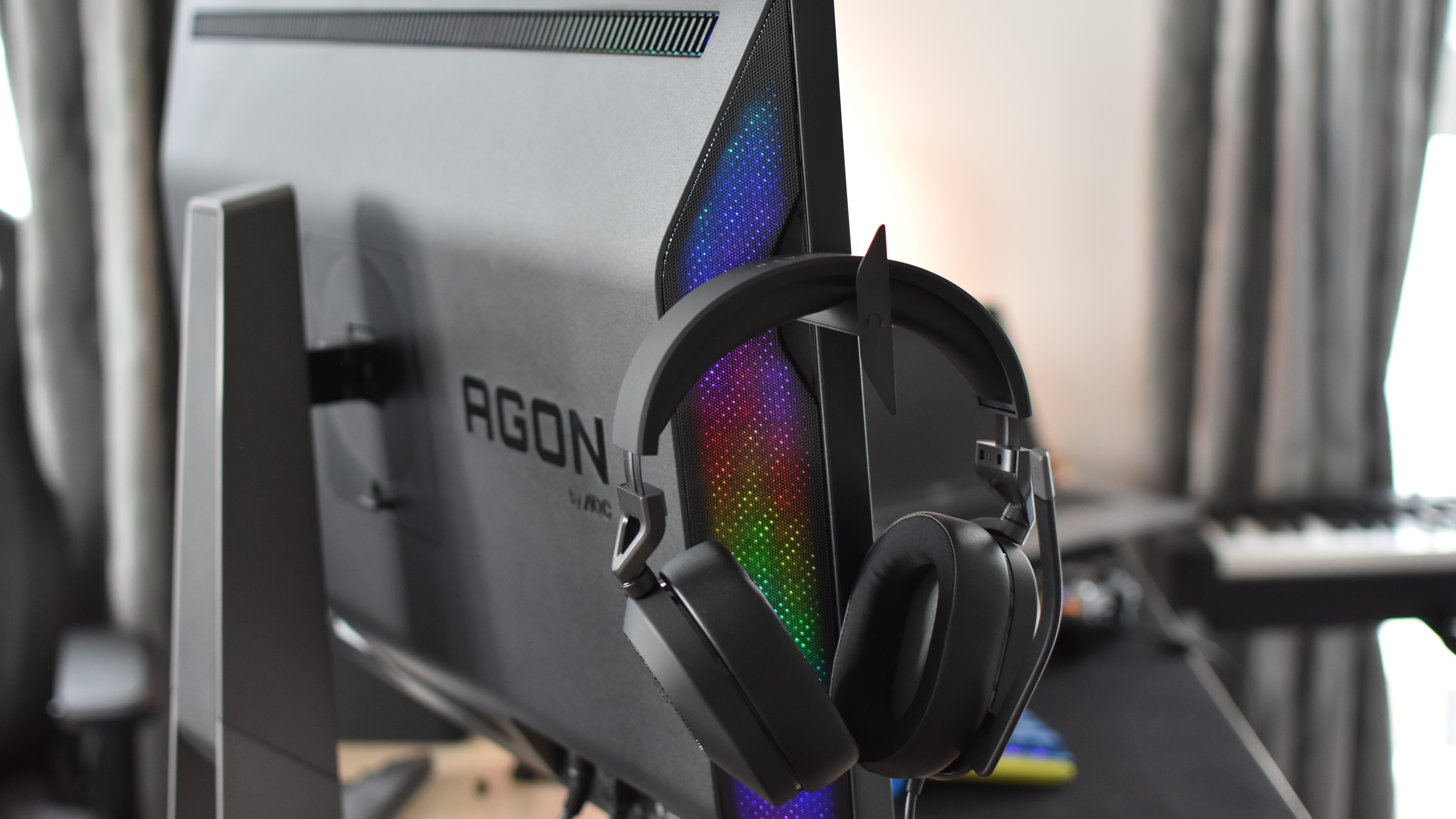 A headset resting on one of the Porsche Design AOC Agon Pro PD32M monitor's pop-out hooks.