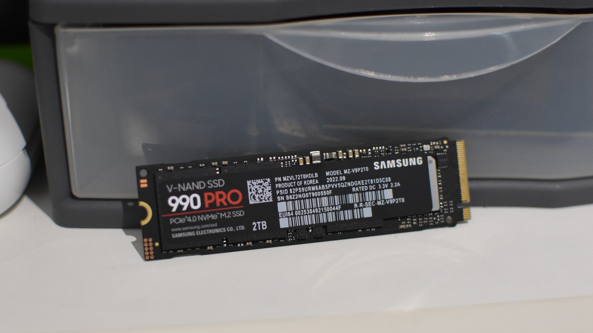 The Samsung 990 Pro SSD leaning against a plastic drawer full of other SSDs.