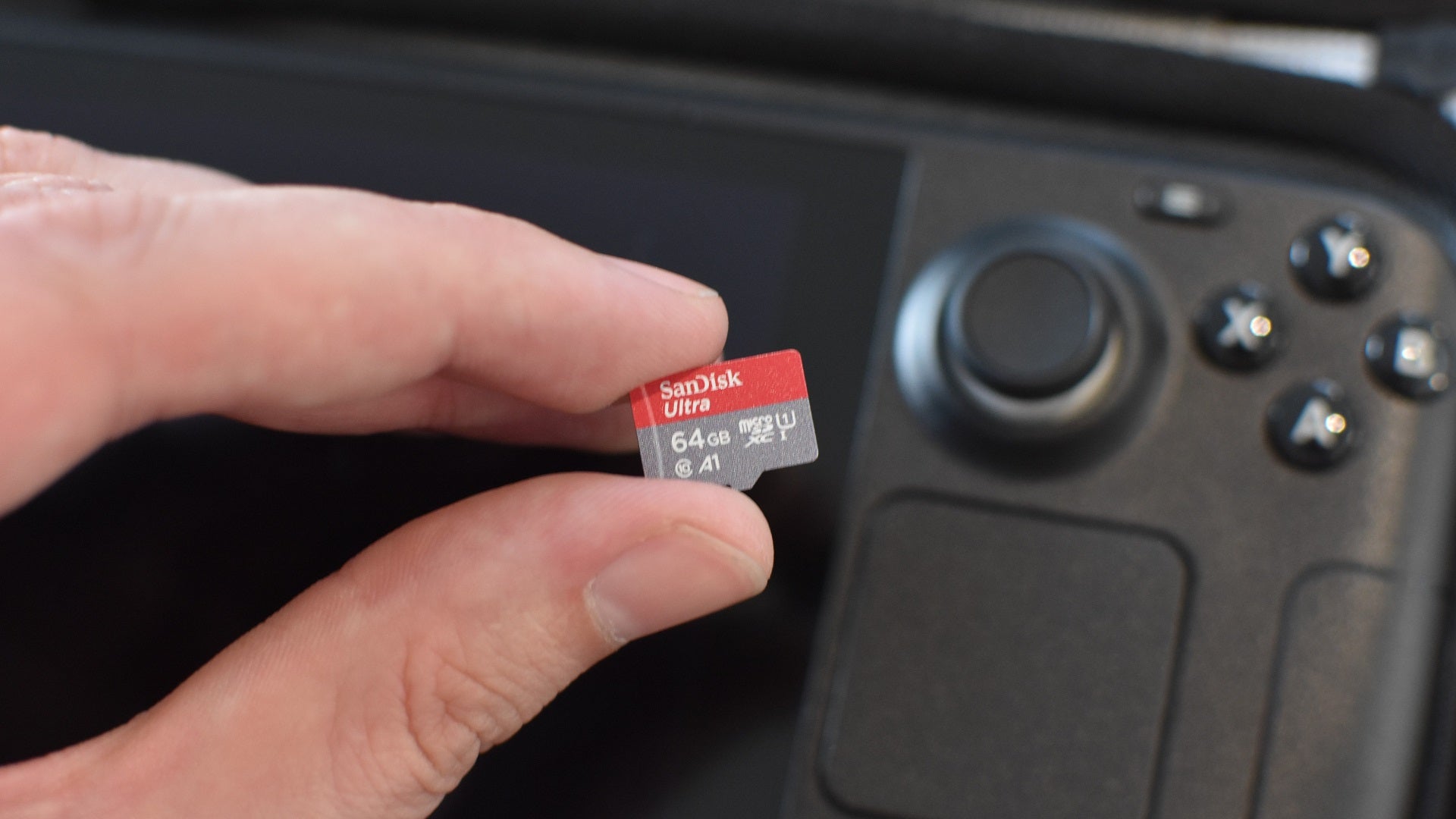 A hand holding the SanDisk Ultra microSD card over a Steam Deck.