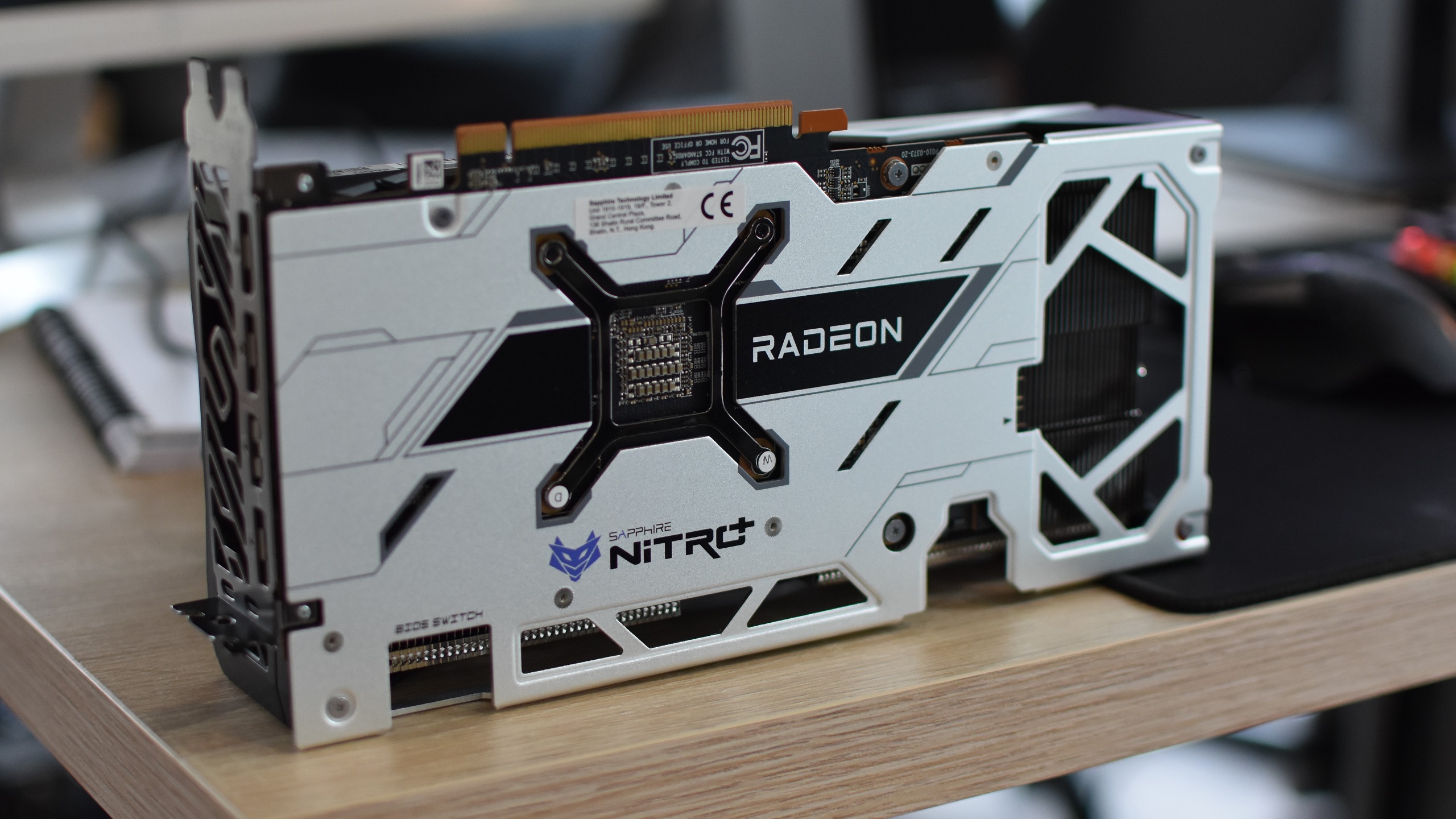 La tarjeta gráfica Sapphire Nitro+ Radeon RX 6650 XT, colocada de lado con la placa posterior a la vista, sobre un escritorio.