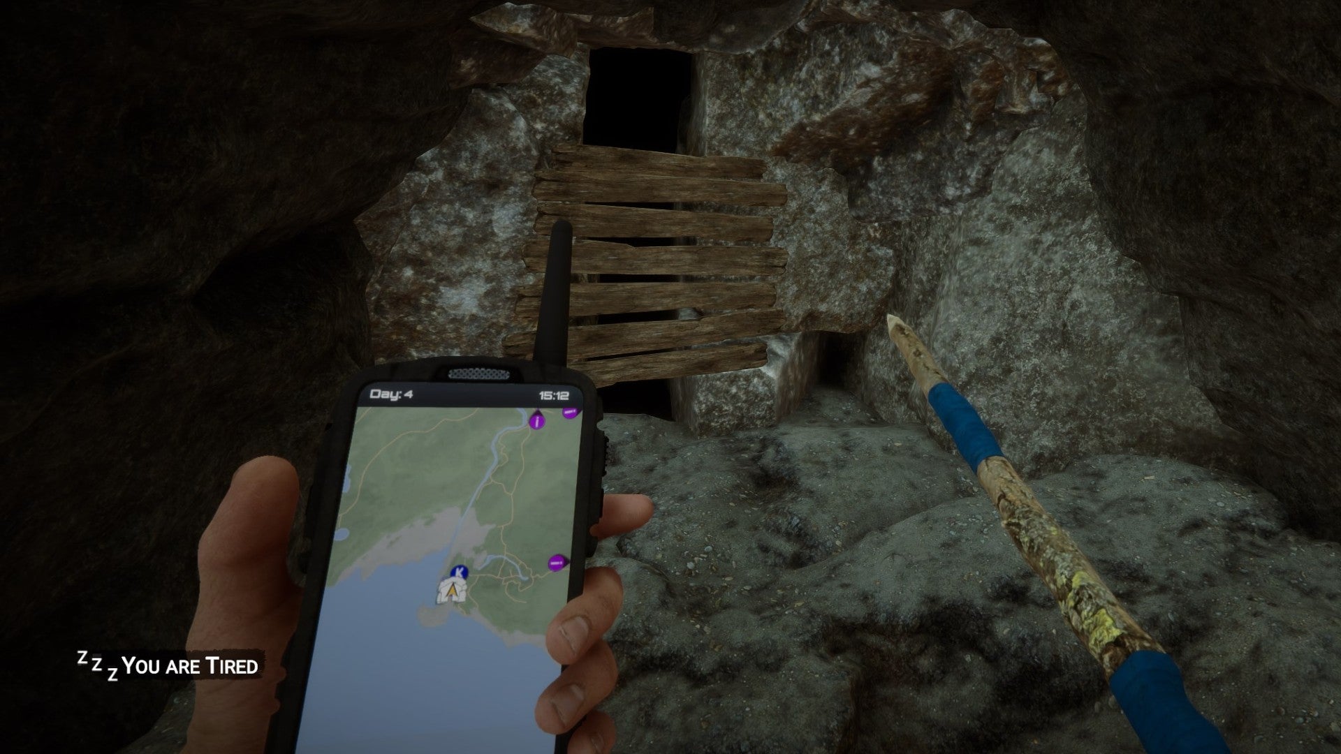 A player stands by a cave entrance with their GPS out in Sons of the Forest.