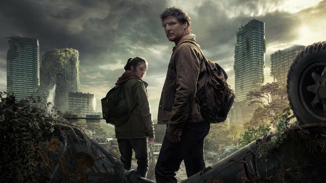 A promo shot of Joel and Ellie from The Last Of Us HBO TV show showing them looking over their shoulders in front of a ruined city