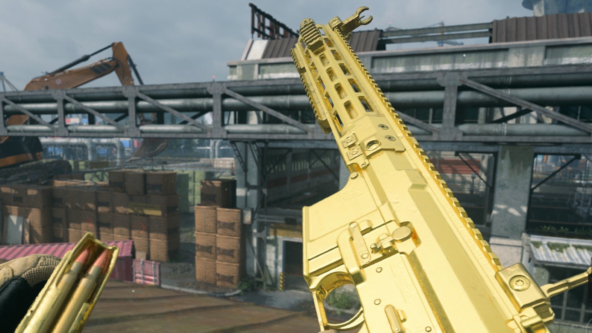 Warzone 2 image showing the M4 looking very pretty and gold, as the player stands on a rooftop overlooking a large warehouse.