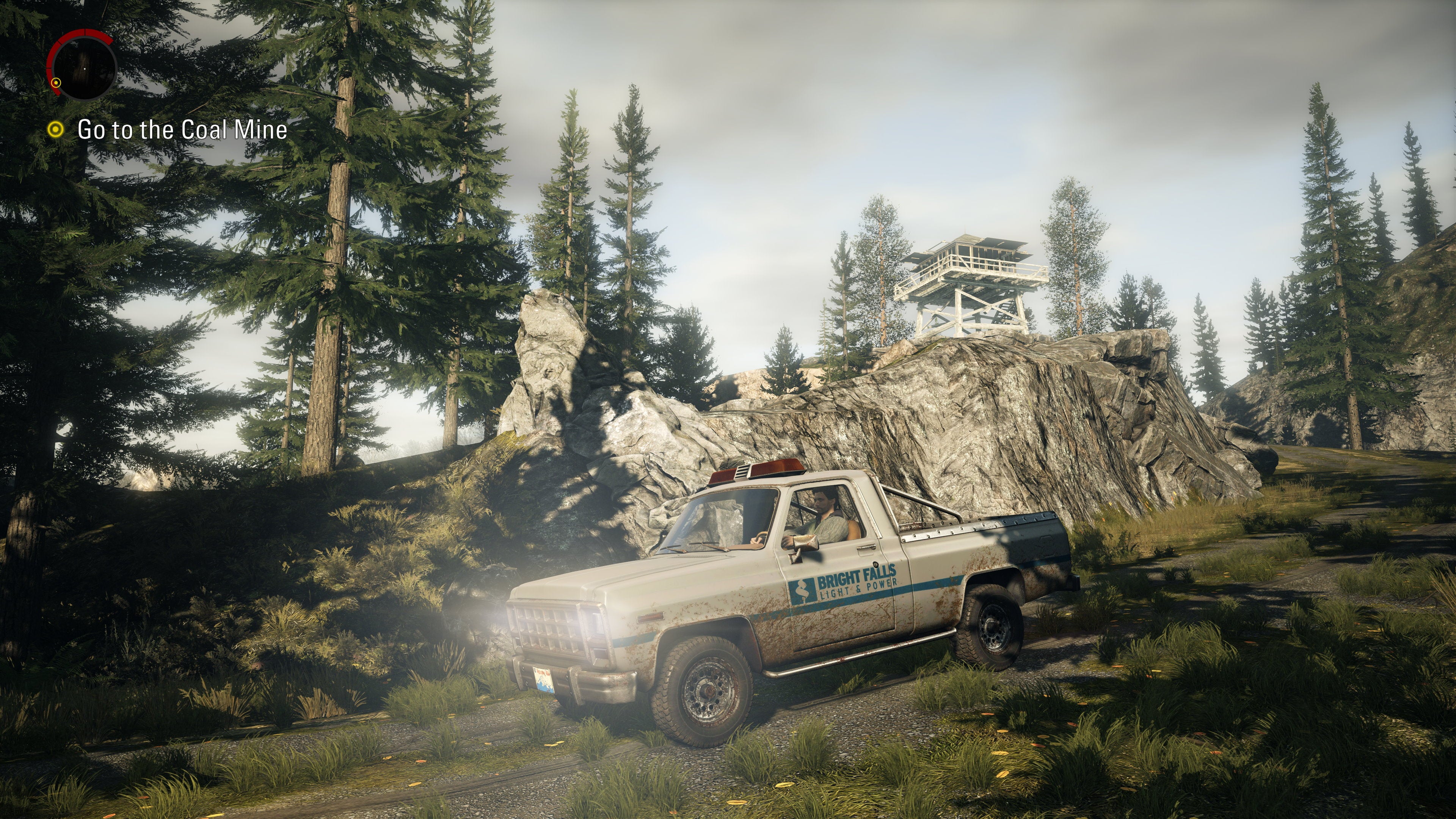 Alan Wake drives a truck through a forest in Alan Wake Remastered