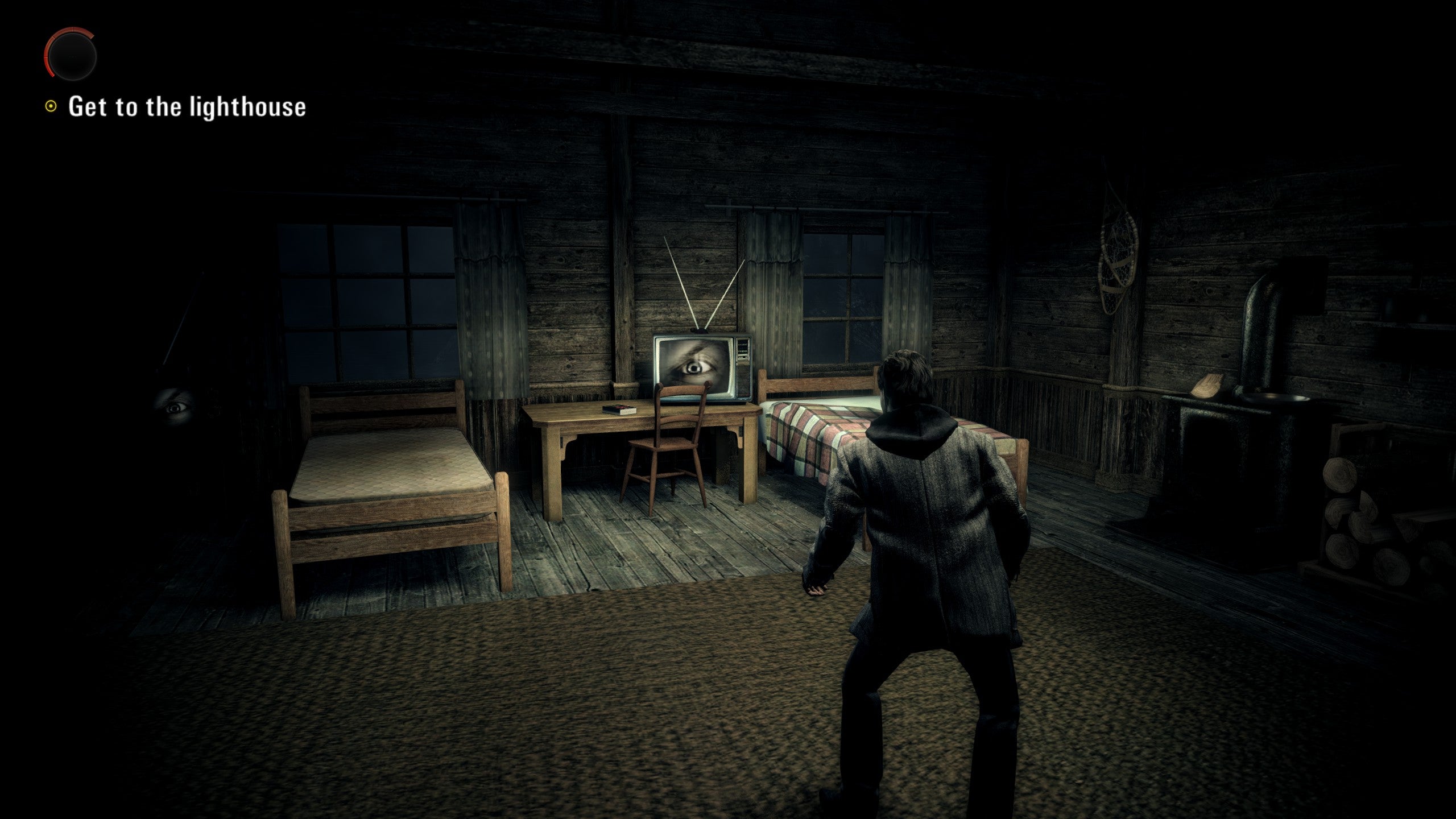 A screenshot of Alan Wake, showing Alan in a darkened cabin.
