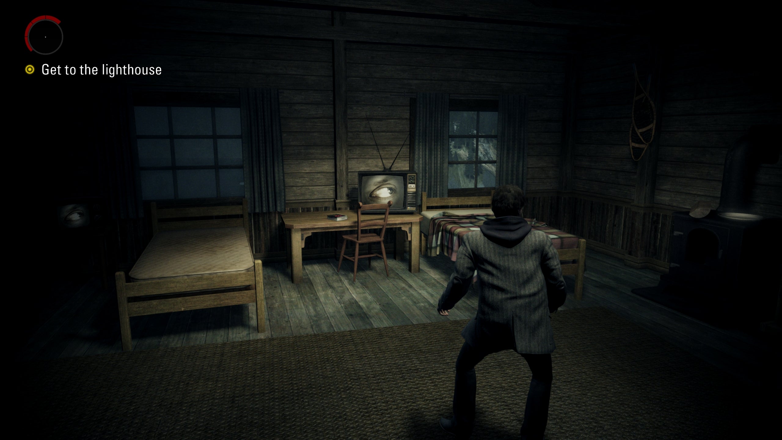 A screenshot of Alan Wake Remastered, showing Alan inside a darkened shack.