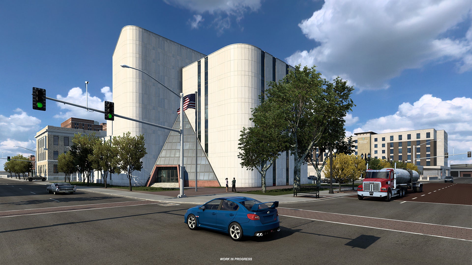 American Truck Simulator Texas - Cars drive through a city intersection.
