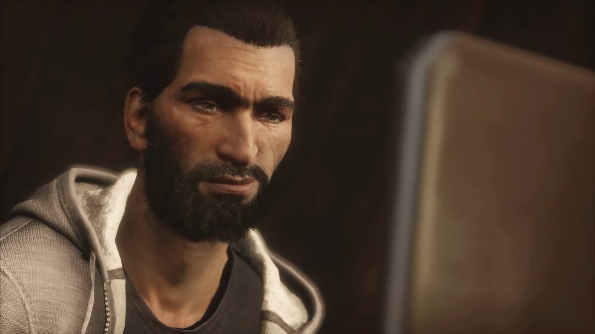 A close-up of Basim, a character in the modern day storyline of Assassin's Creed Valhalla, staring at a laptop screen.