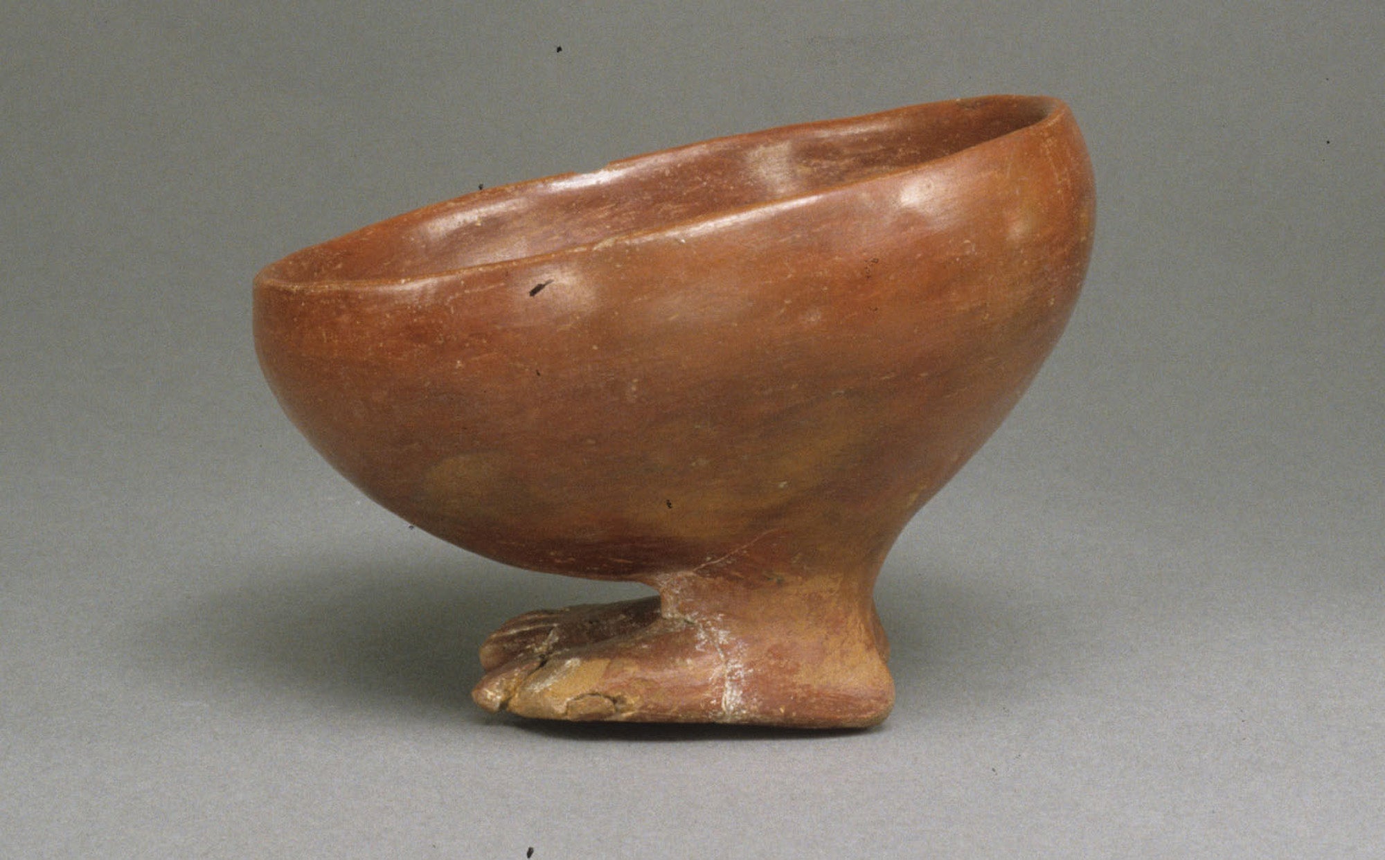 A little rounded brown orange bowl standing on human-shaped feet, from predynastic Egypt circa 3900 –3650 B.C.