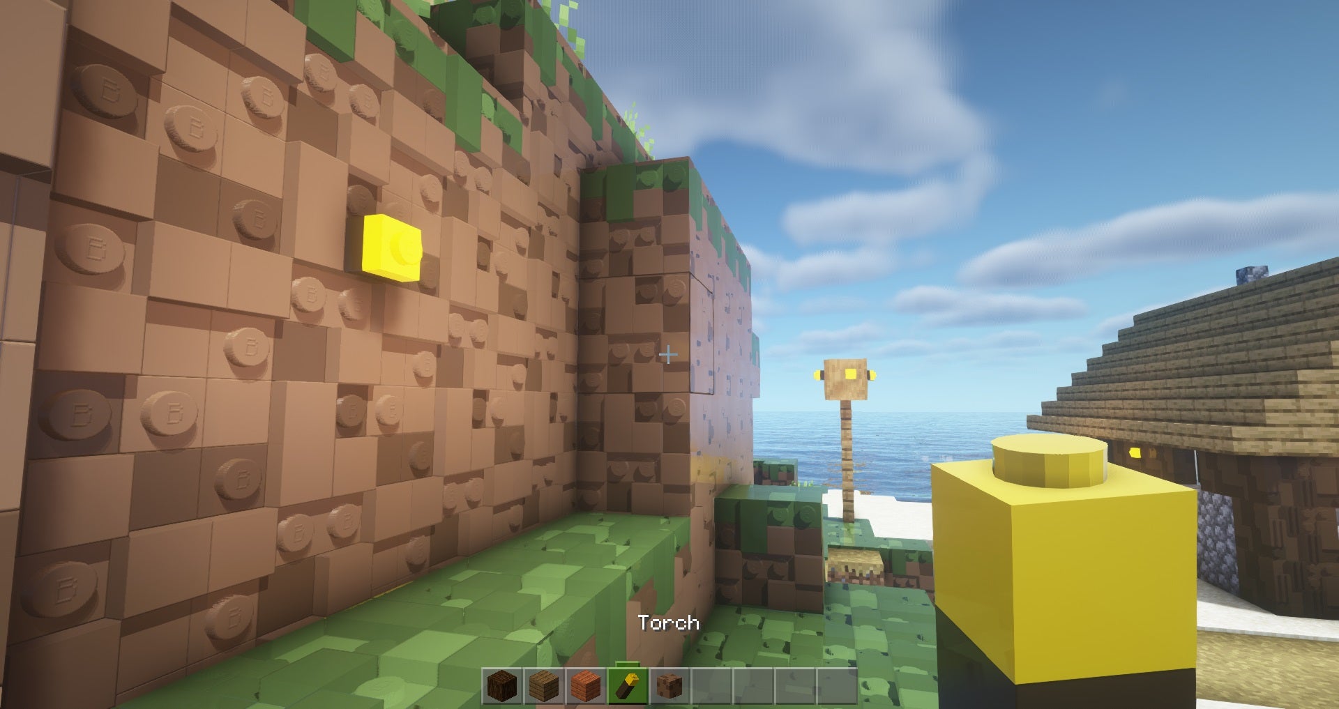 Brixel resource pack for Minecraft - A screenshot of a player holding a Lego-like torch while looking at a dirt cliff that also appears made of Lego-style bricks.