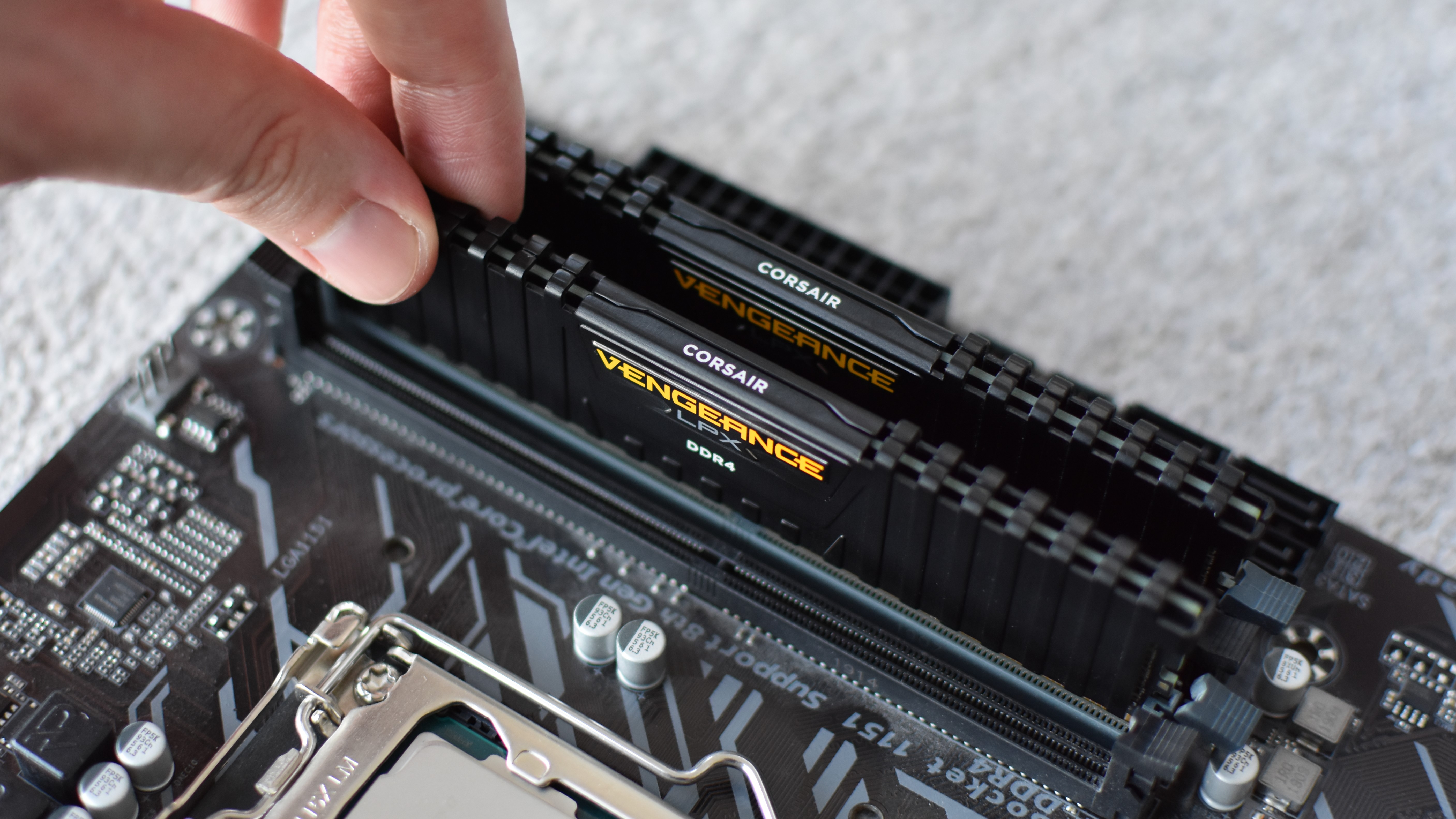 Two sticks of DDR4 RAM being installed in a motherboard.