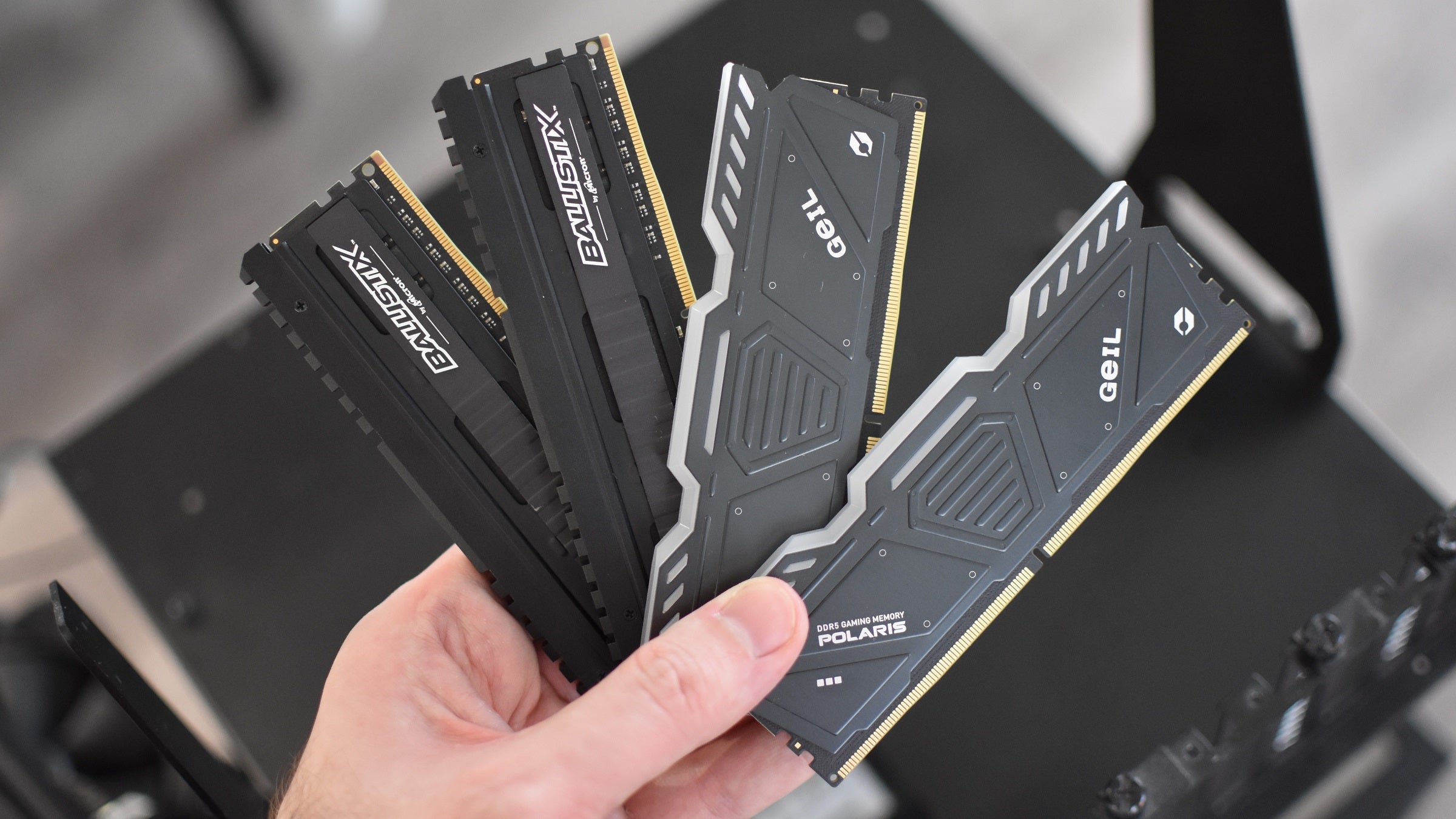 Some DDR4 and DDR5 RAM modules, fanned out and held in one hand.