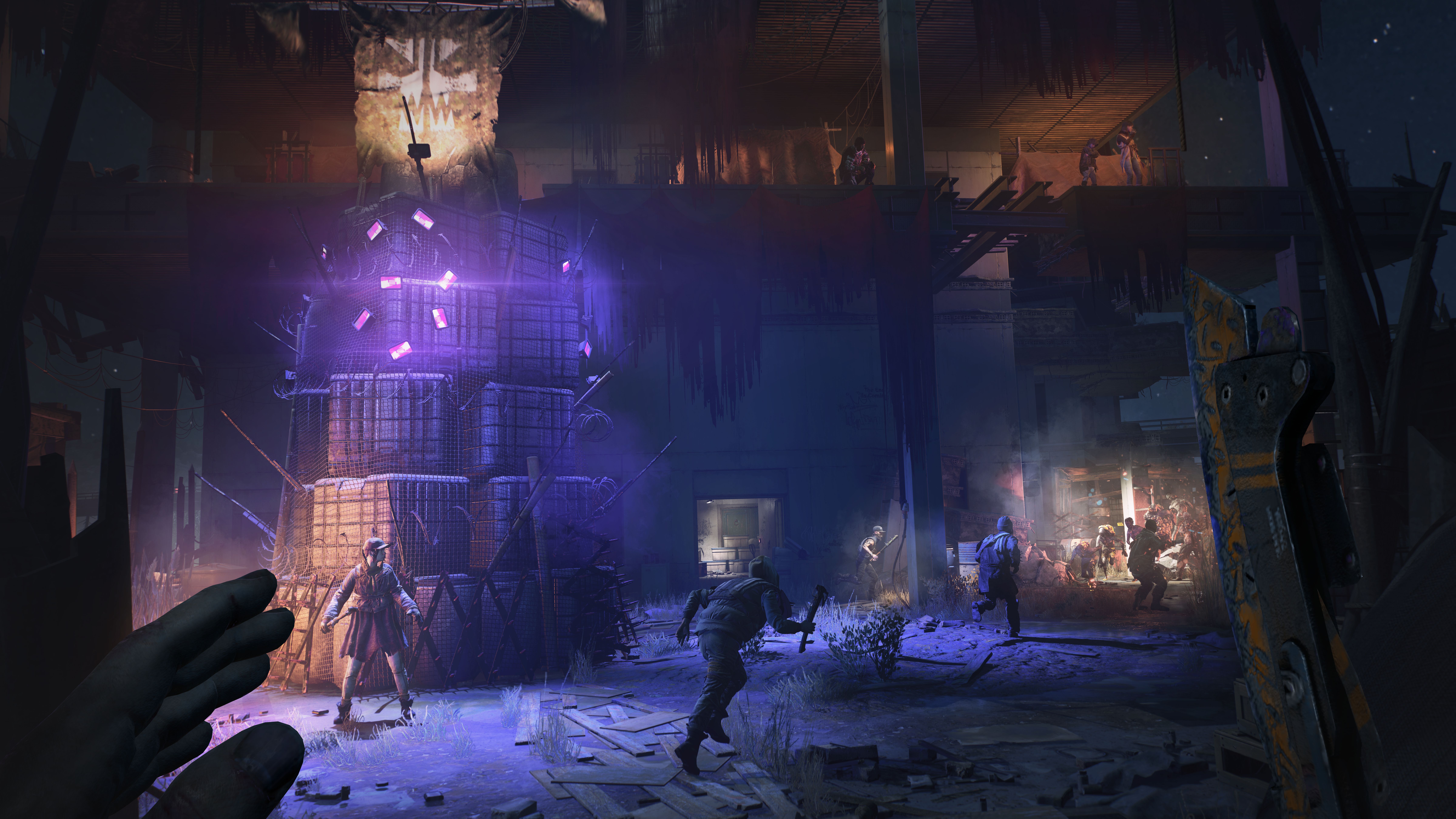 A promotional screenshot from a preview of Dying Light 2, showing the inside of a bandit hideout lit in purple, with a heap of storage crates piled into what looks like a kind of bad-guy Christmas tree