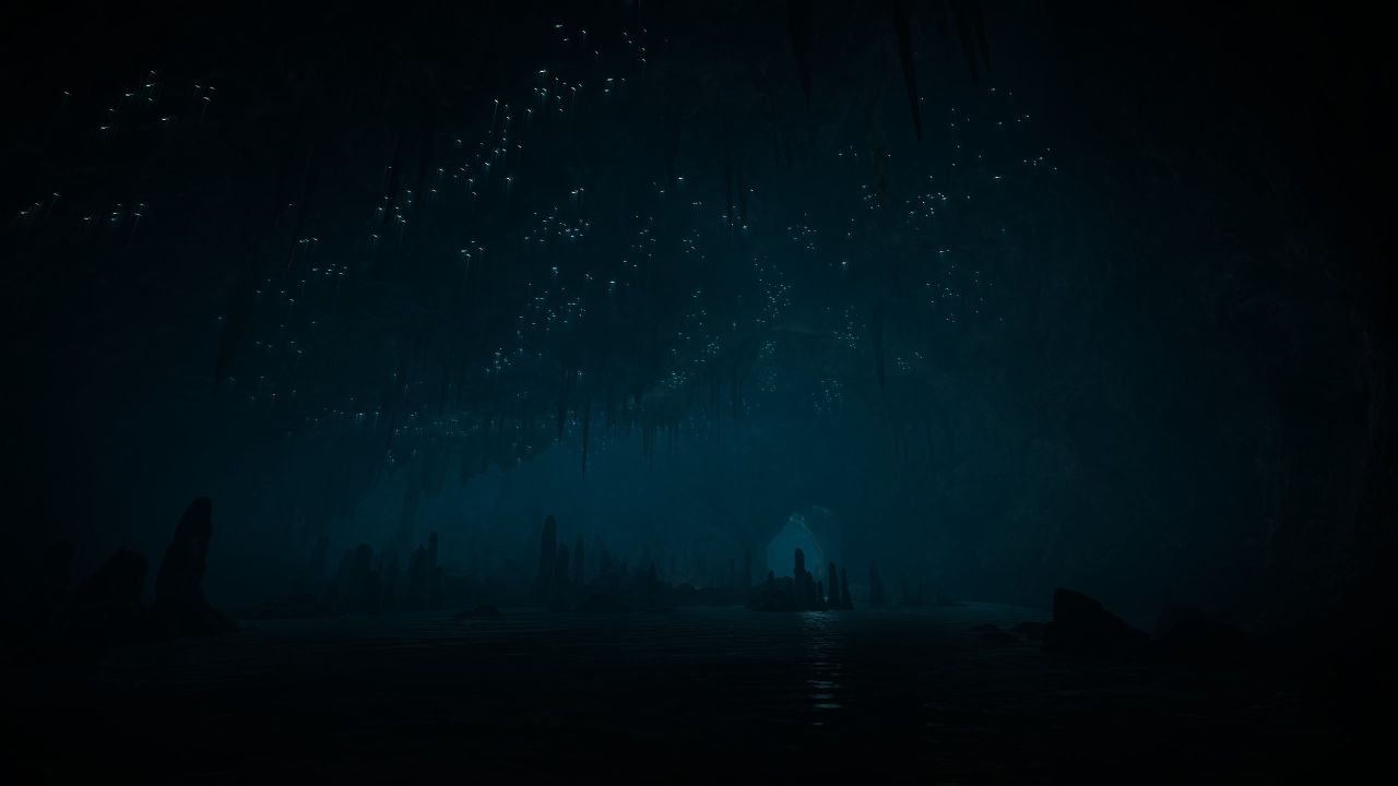 A screen shot of the deep, dark cave in Eastshade, stalactites and stalagmites dimly visible and tiny pinpricks of light on the ceiling that look like stars