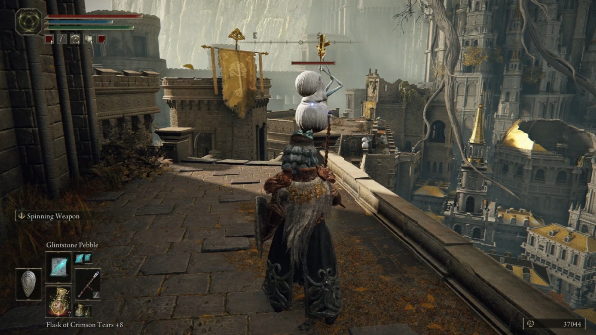 Elden Ring player stands on a walkway overlooking a ruined city. They aim at an enemy that looks like a snowman playing a trumpet.