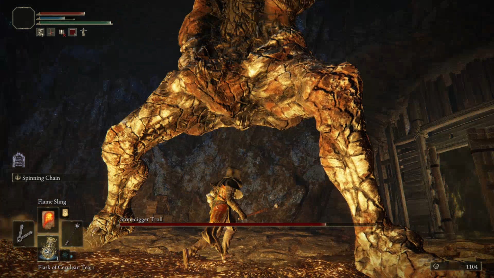 A close-up of the player in Elden Ring slipping between the legs of the Stonedigger Troll boss.