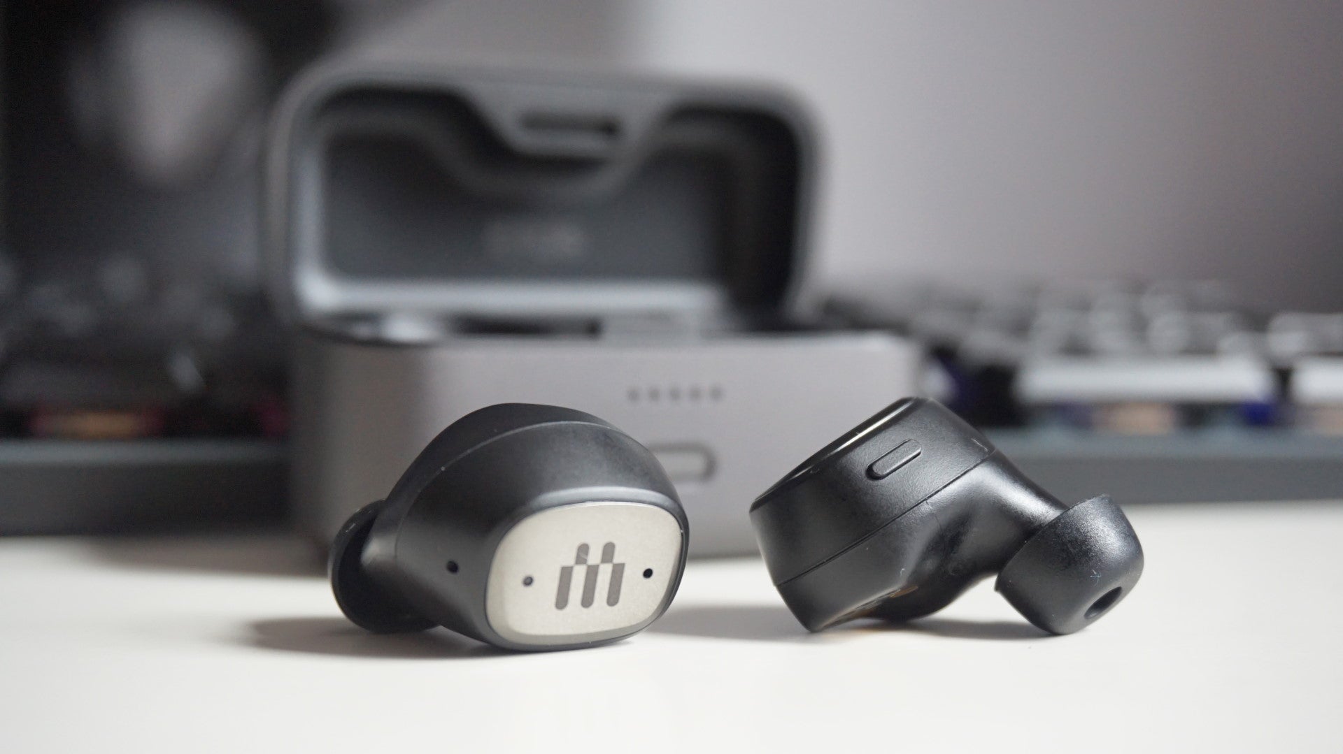 A photo of the EPOS GTW 270 Hybrid wireless earbuds in front of their charging case