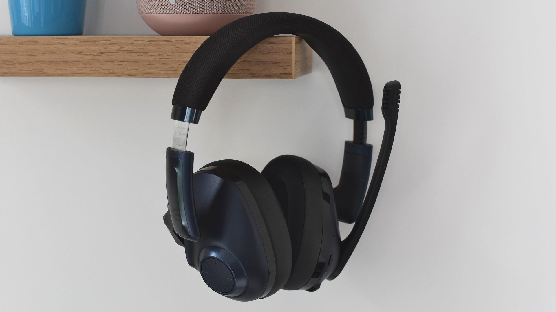 The EPOS H3Pro Hybrid gaming headset hanging from the corner of a shelf.