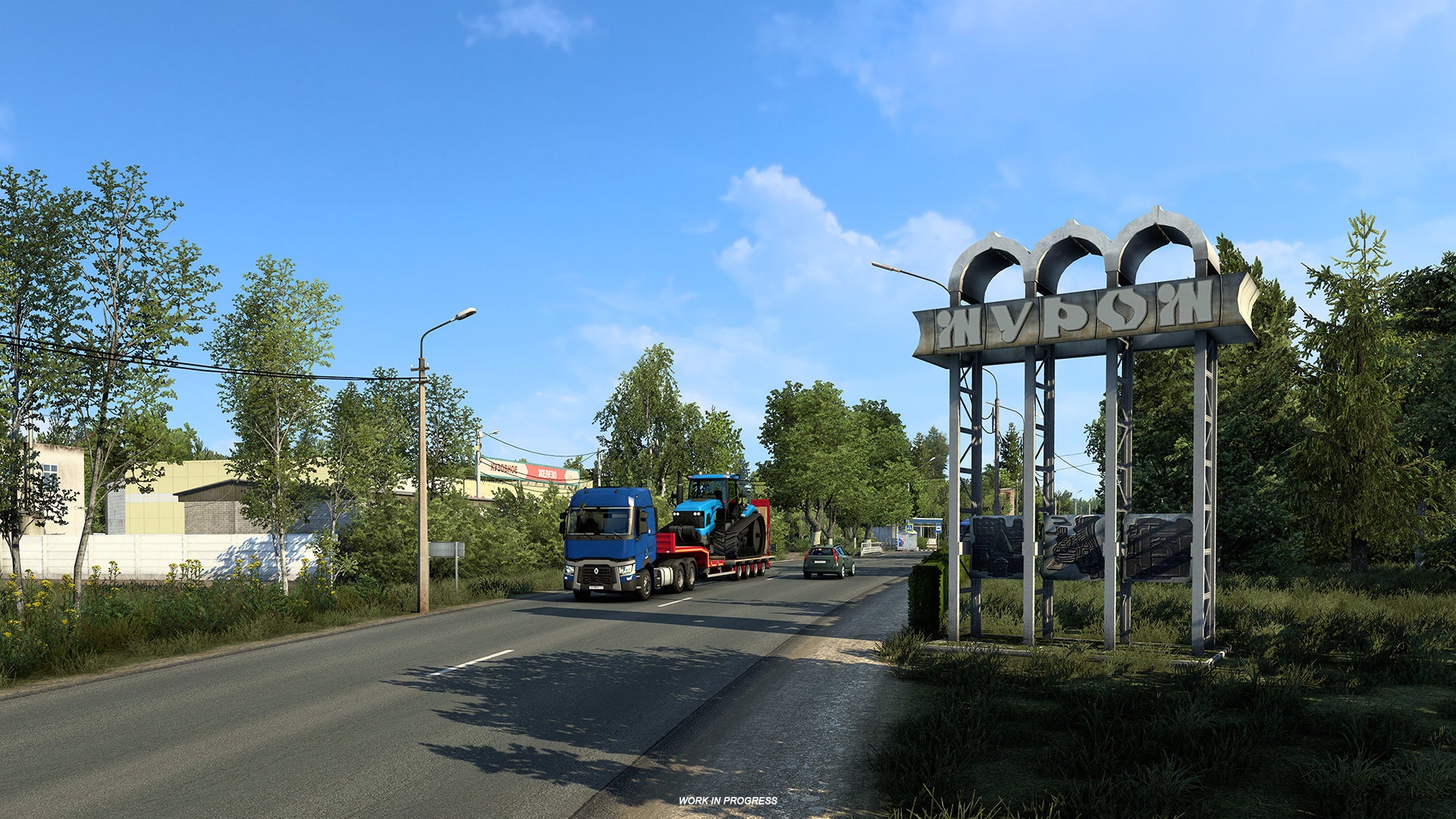 A screenshot of Euro Truck Simulator 2's coming Heart Of Russia DLC showing a lorry with a tractor on its back driving past the metal entrance sign to a city.