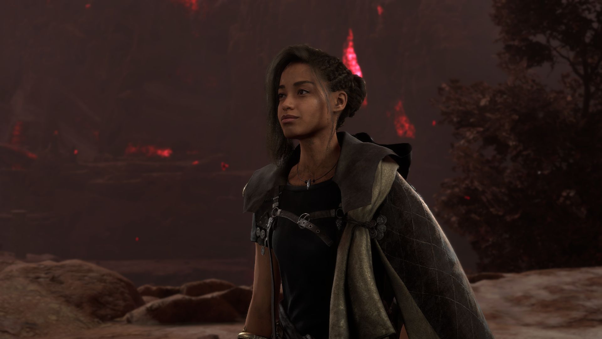 Frey, the protagonist of Forspoken, a young Black woman wearing a fantasy-y grey cape, standing against a rocky red-and-grey landscape