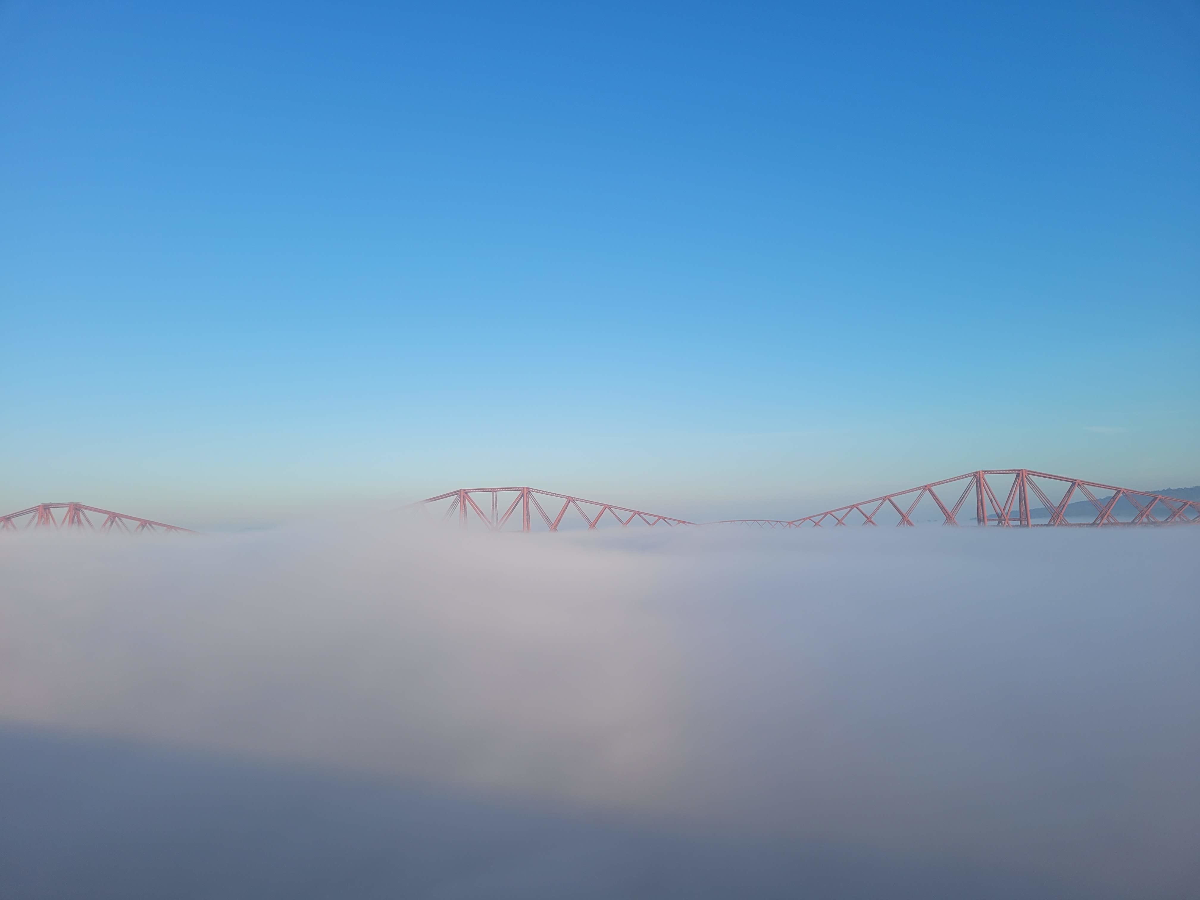 A photograph of Forth Bridge emerging from thick cloud.