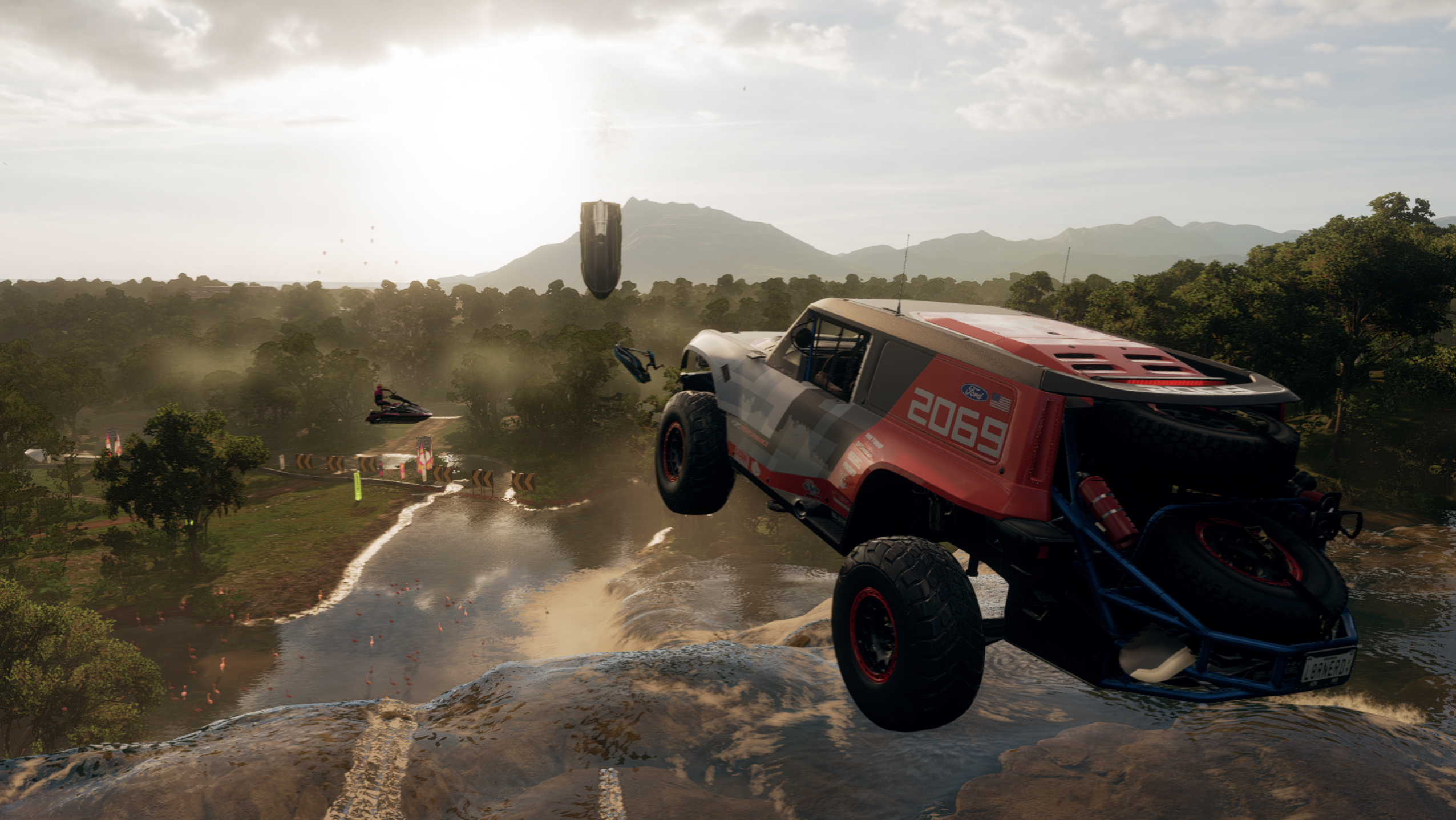 In Forza Horizon 5, a truck catches air while racing three jet ski riders down a river.