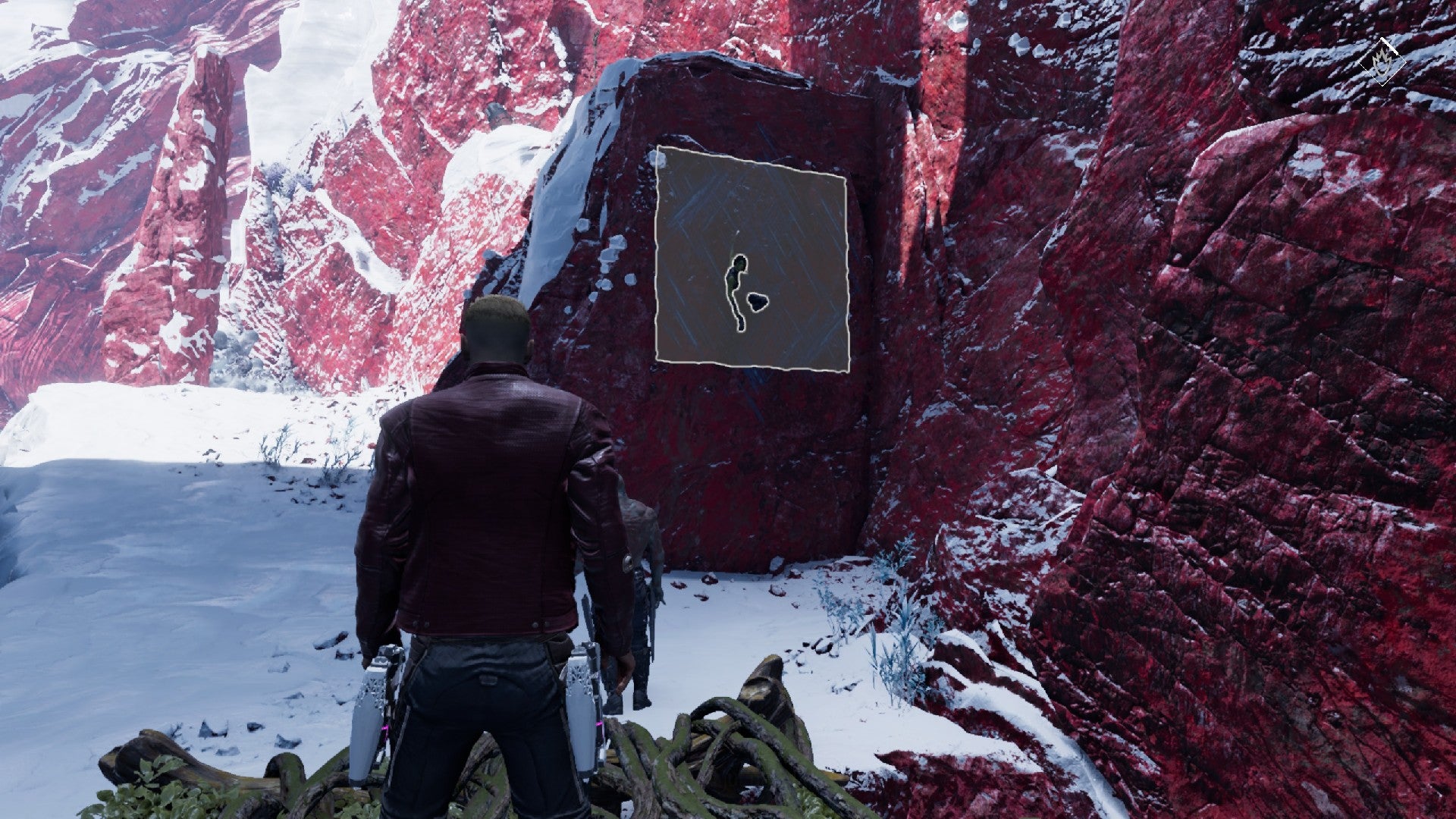 Gamora hangs from a cliff face, Star Lord stands in the snow below. Red mountains surround them