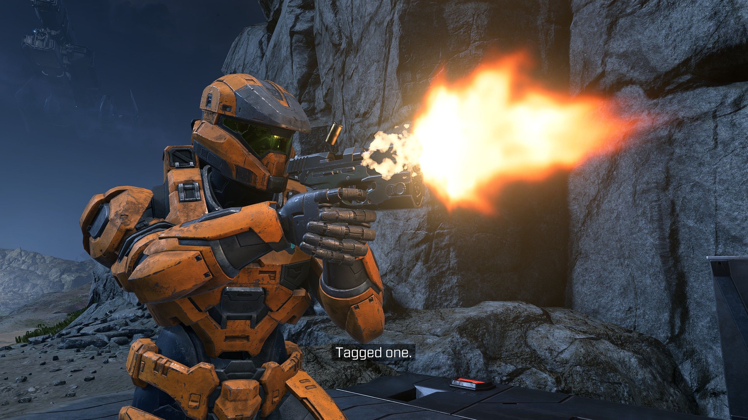 A Spartan soldier in orange armour firing their pistol in a close up screenshot