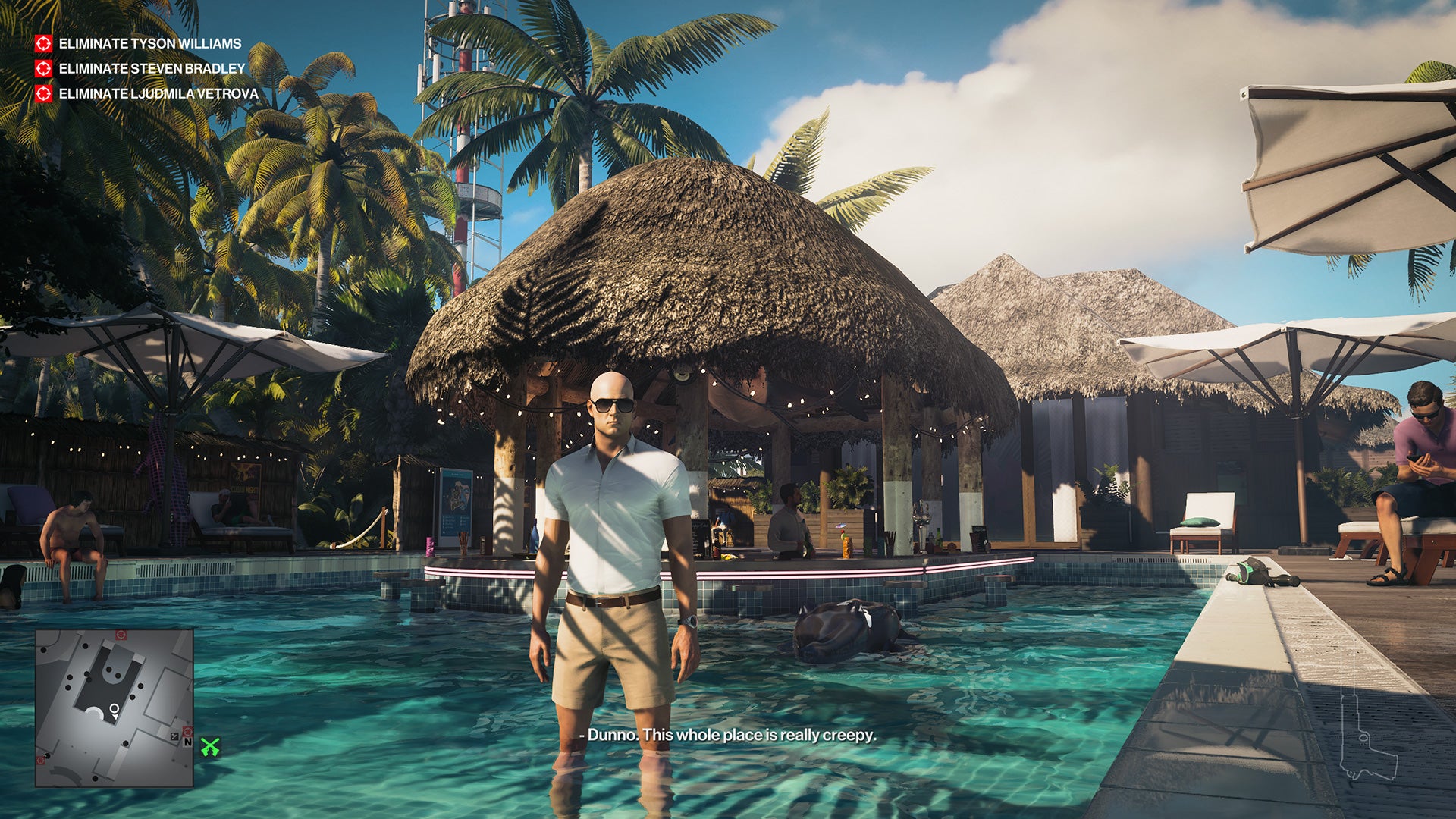 Ian Hitman stands in a pool in front of a swanky pool bar. He's wearing shorts and a white shirt, and looks like he might be on a normal holiday, almost.