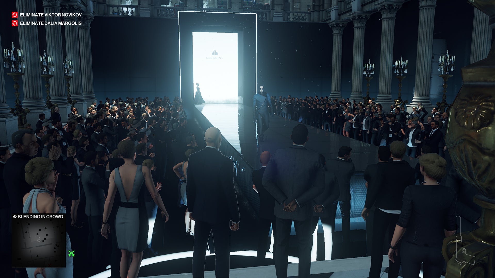 A screenshot of the Paris level, showing Ian Hitman standing at the end of a long, sleek, fashion runway, watching from the crowd as models walk down.