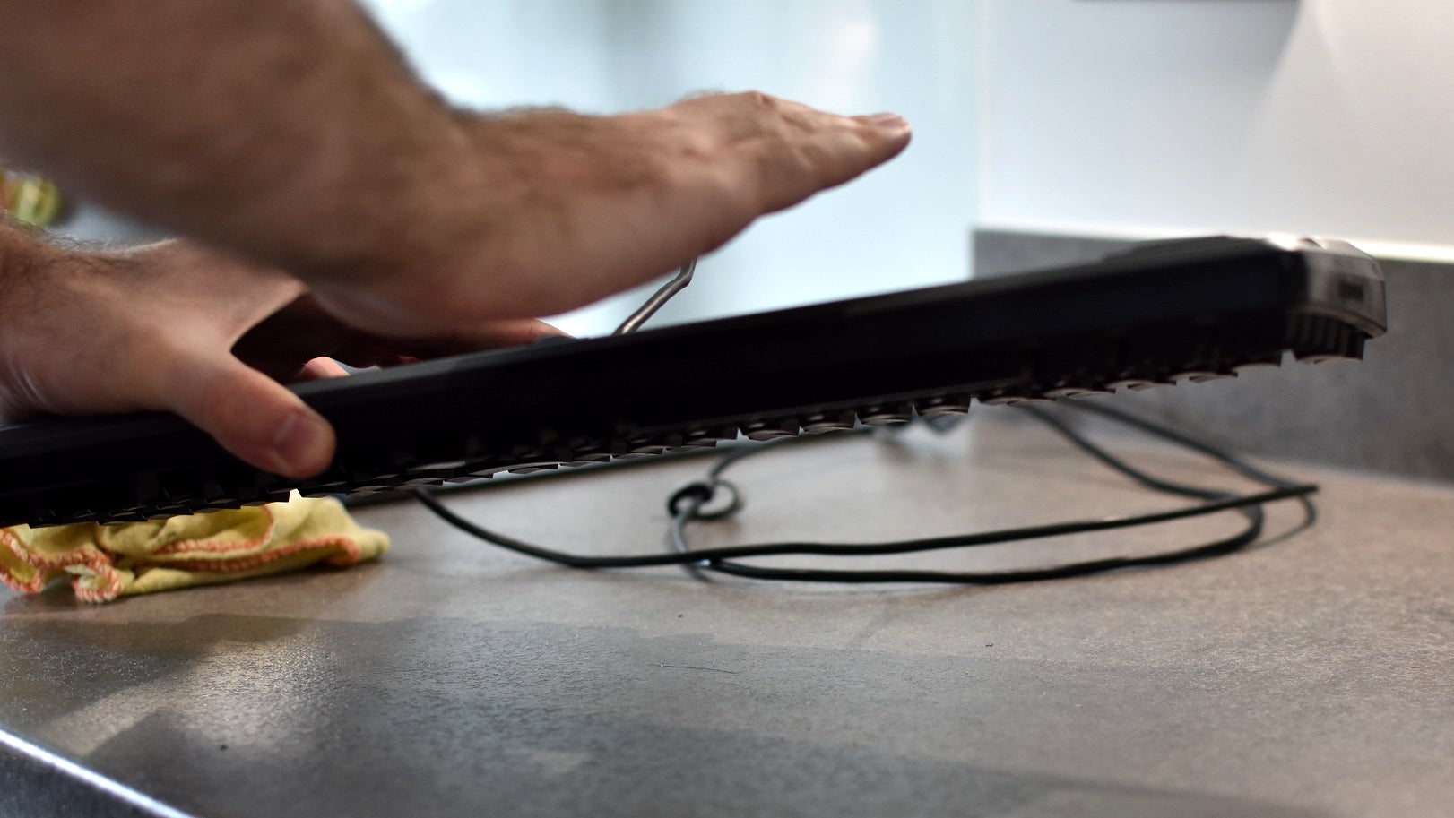A keyboard being held upside down and shaken, so that dust and dirt falls out.