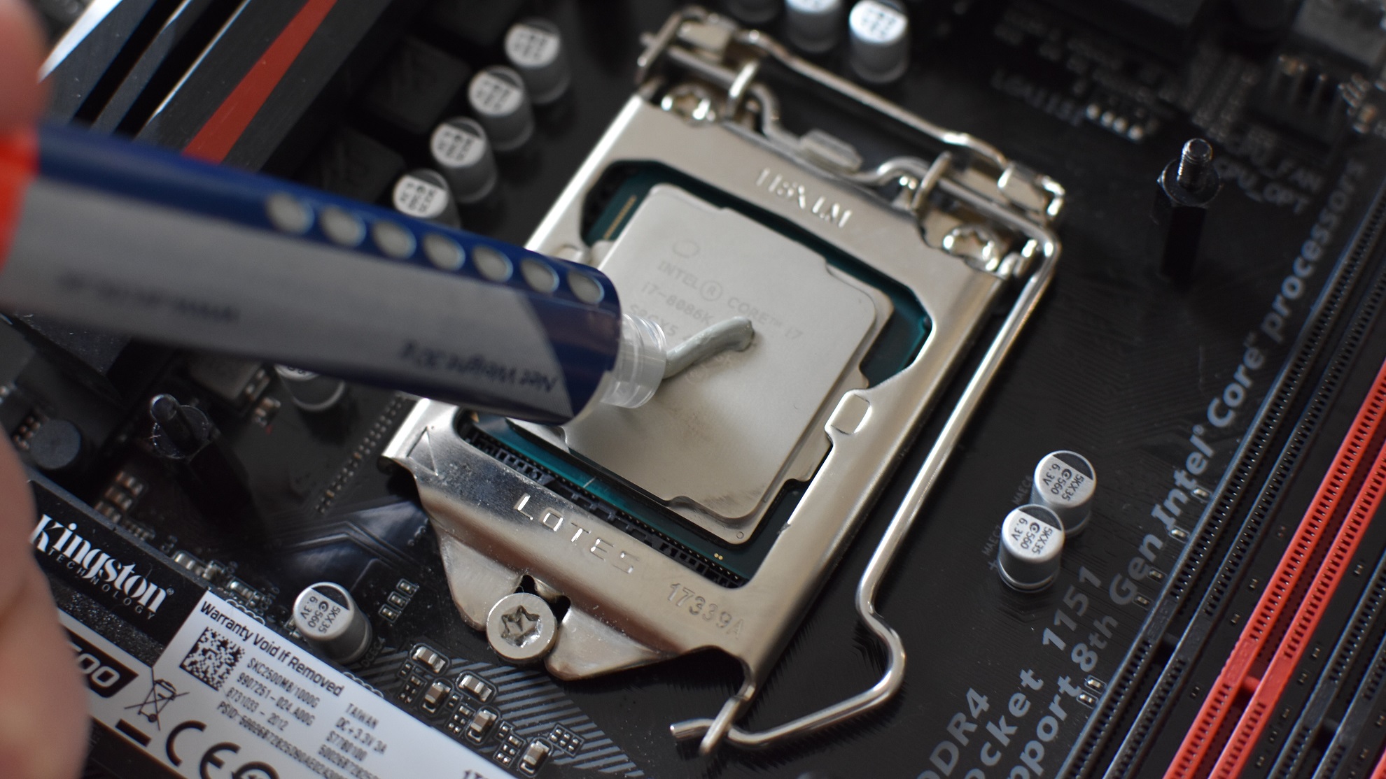 Some thermal paste being squeezed from a tube onto an Intel CPU.