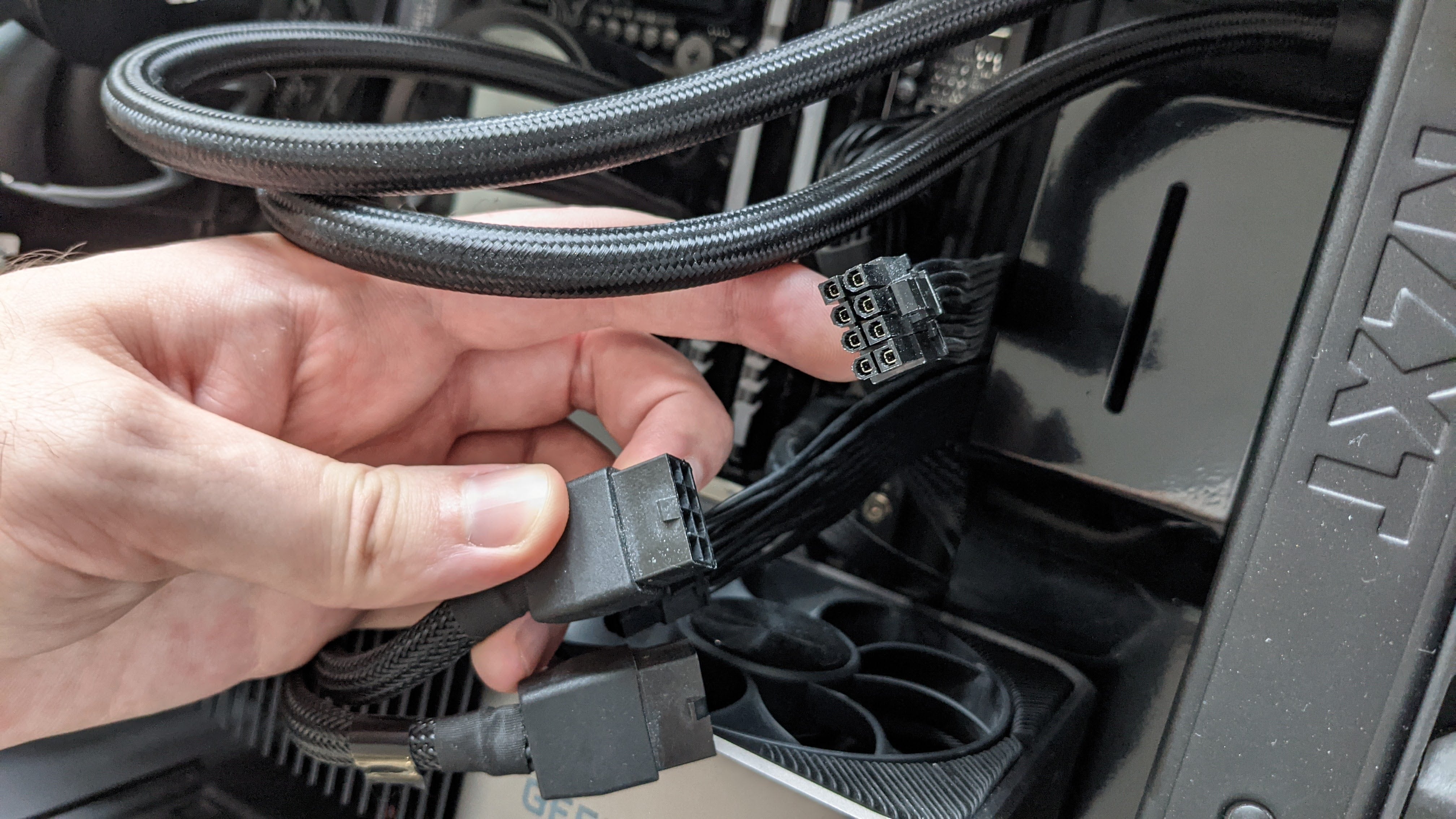 A PCIe power cable being held up next to Nvidia's RTX 30 series power adapter.