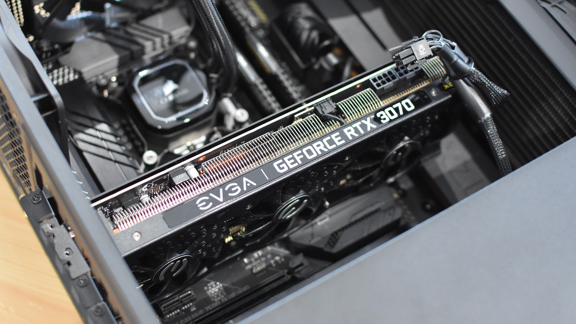 A GeForce RTX 3070 graphics card partially installed in a motherboard, with the PSU cables disconnected.